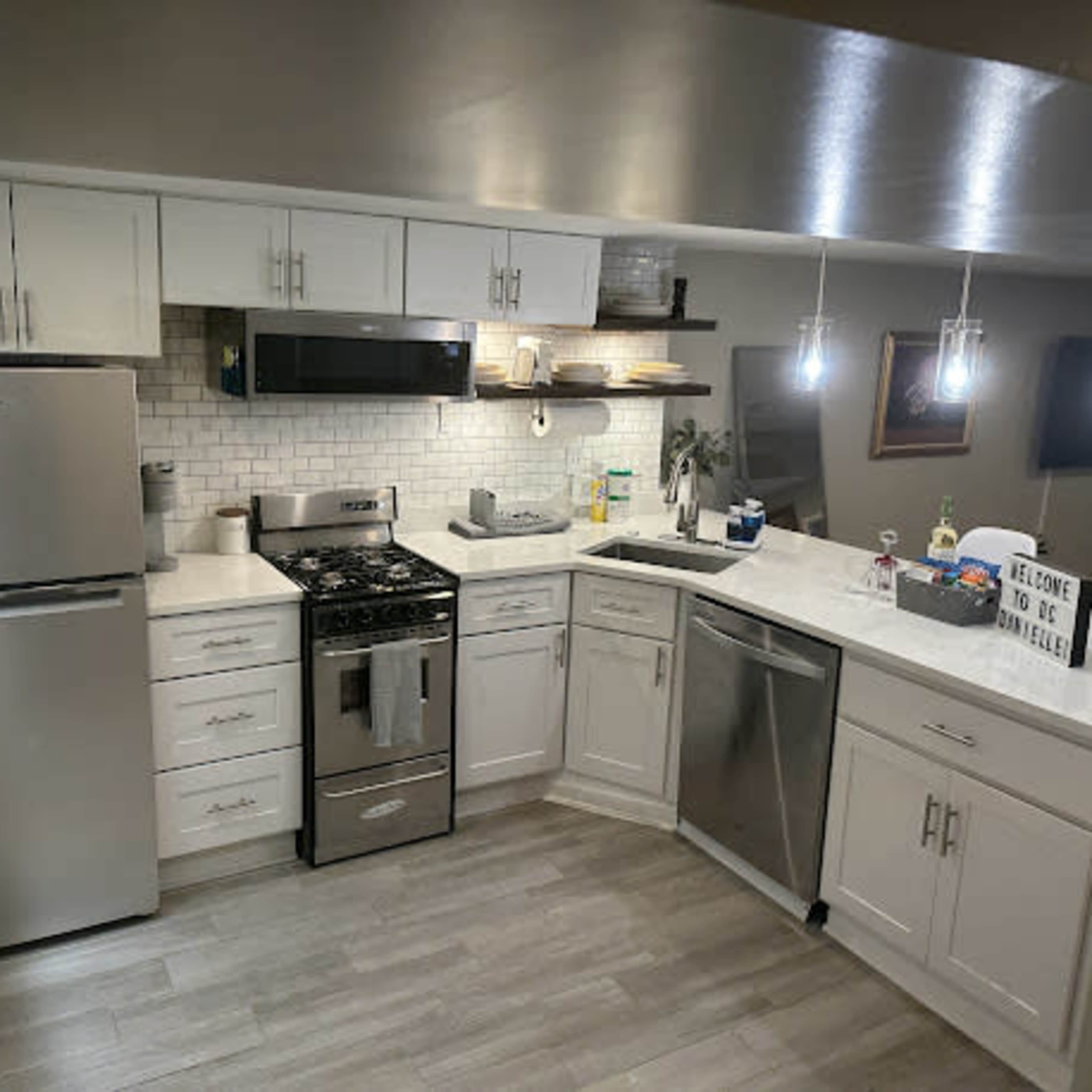 A modern kitchen with white cabinetry, stainless steel appliances, and a light countertop.