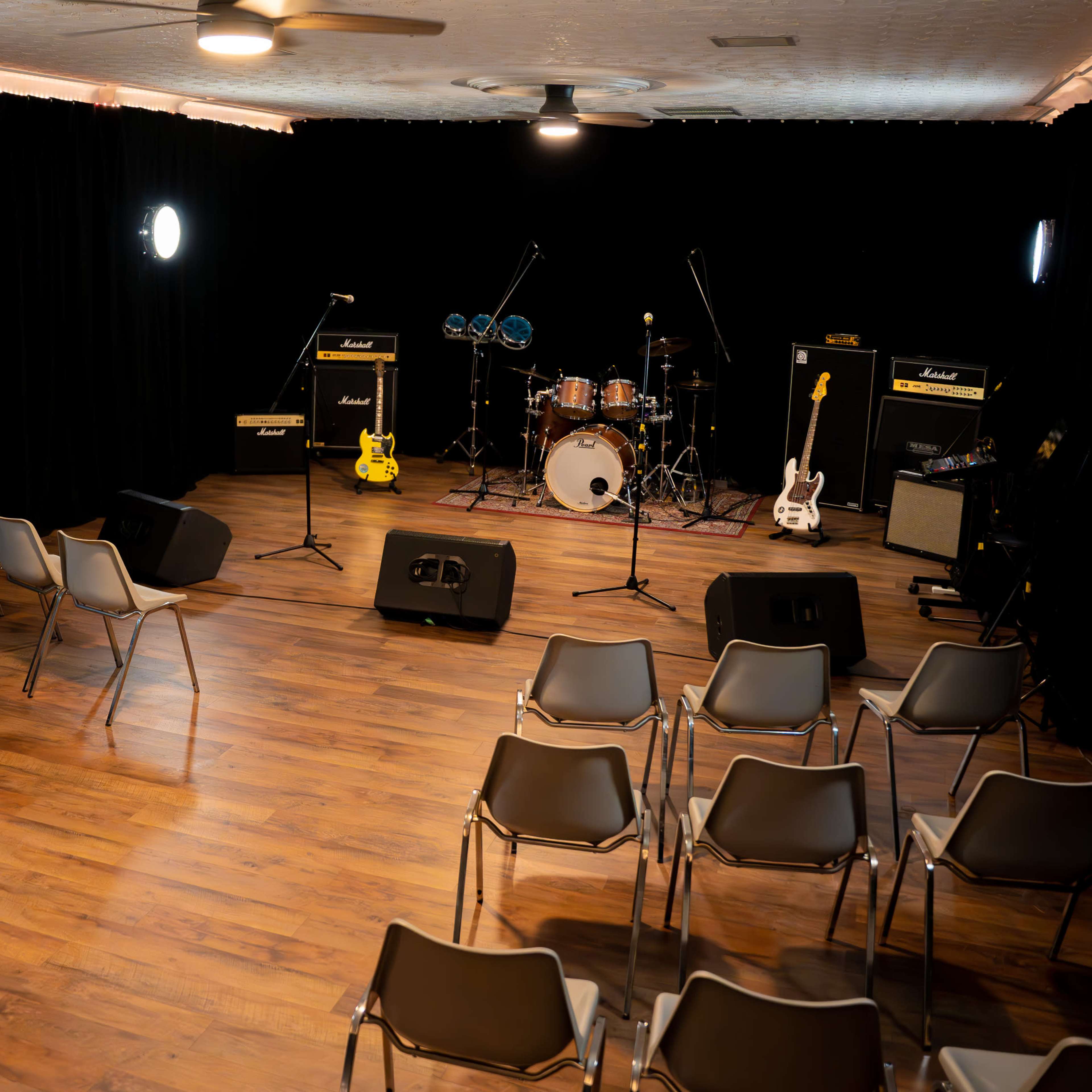 A small stage is set up for a performance, surrounded by empty chairs arranged in rows.