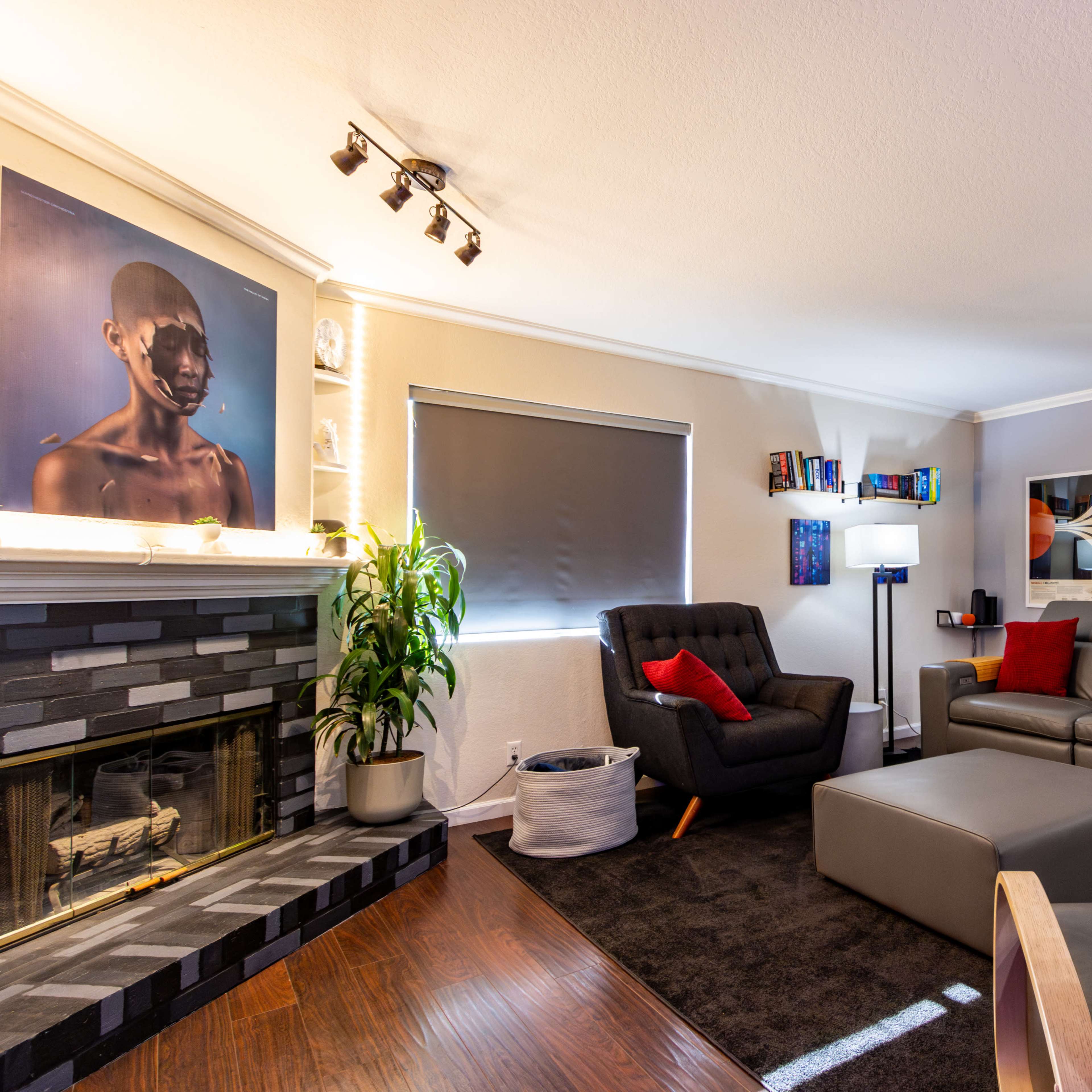 A modern living room with a fireplace, black and gray sofas, a coffee table, and artwork displayed on the walls.