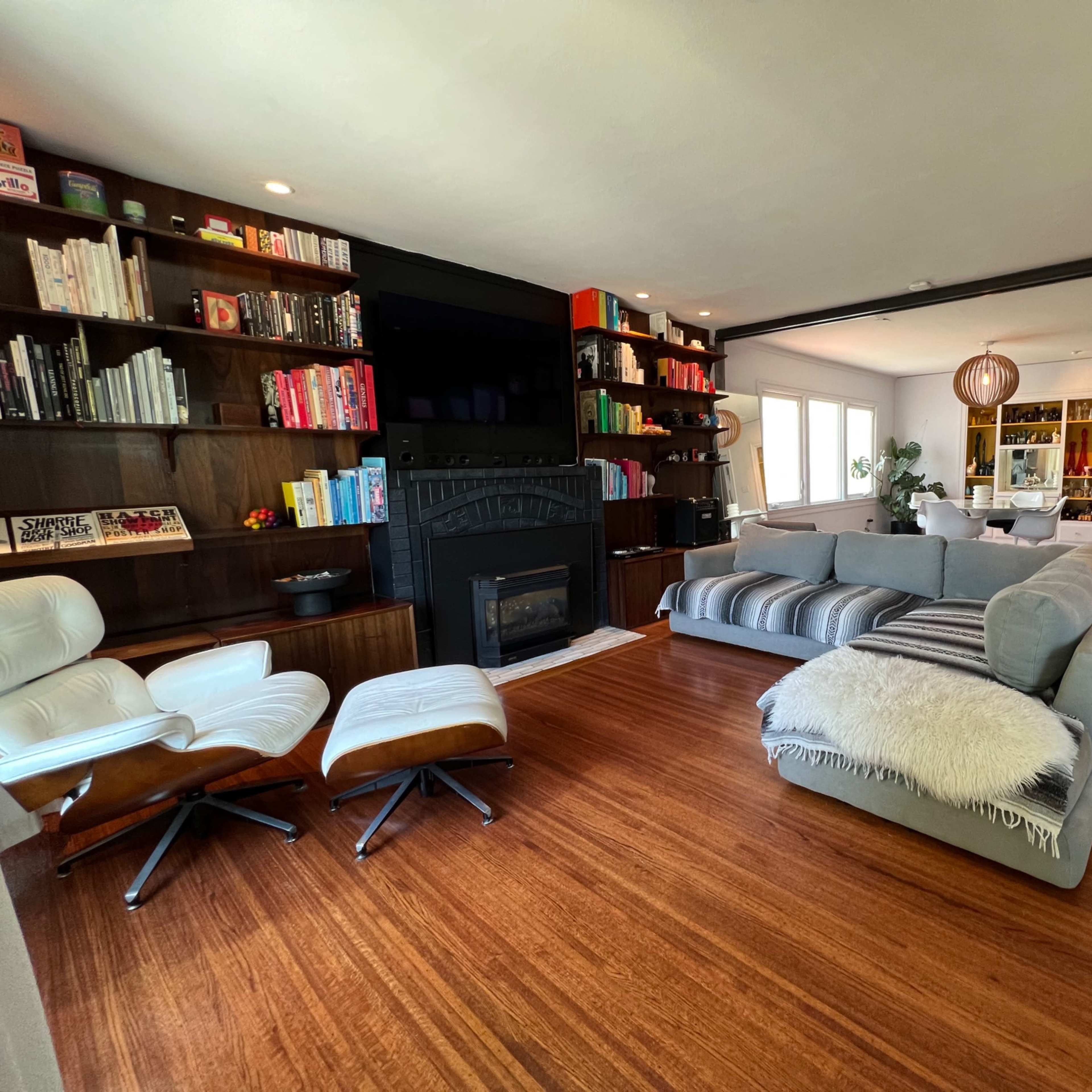 A modern living room with a large sectional sofa, a fireplace, and built-in bookshelves filled with books and decorative items.