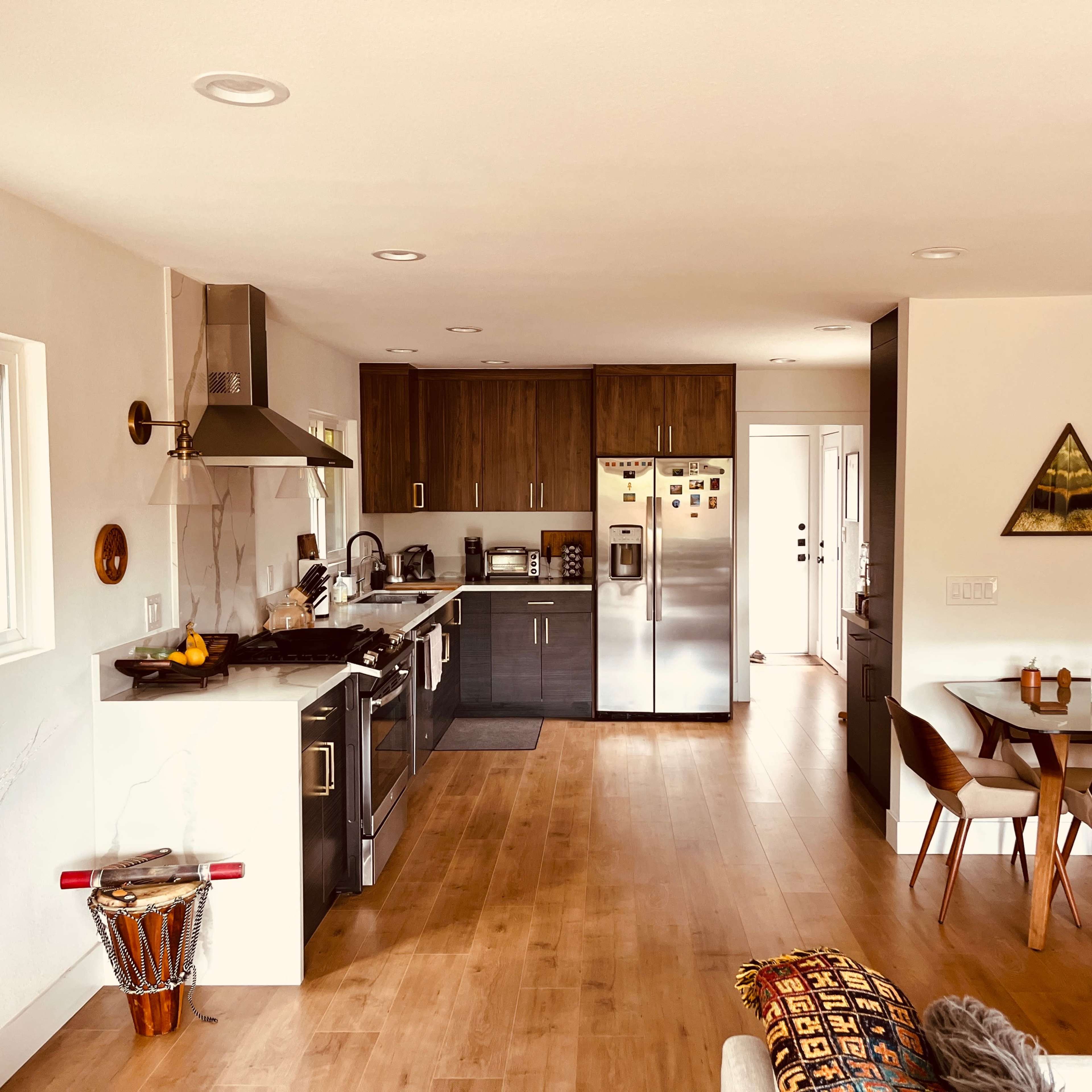 A modern kitchen and dining area with wooden flooring, stainless steel appliances, and a dining table set for four.