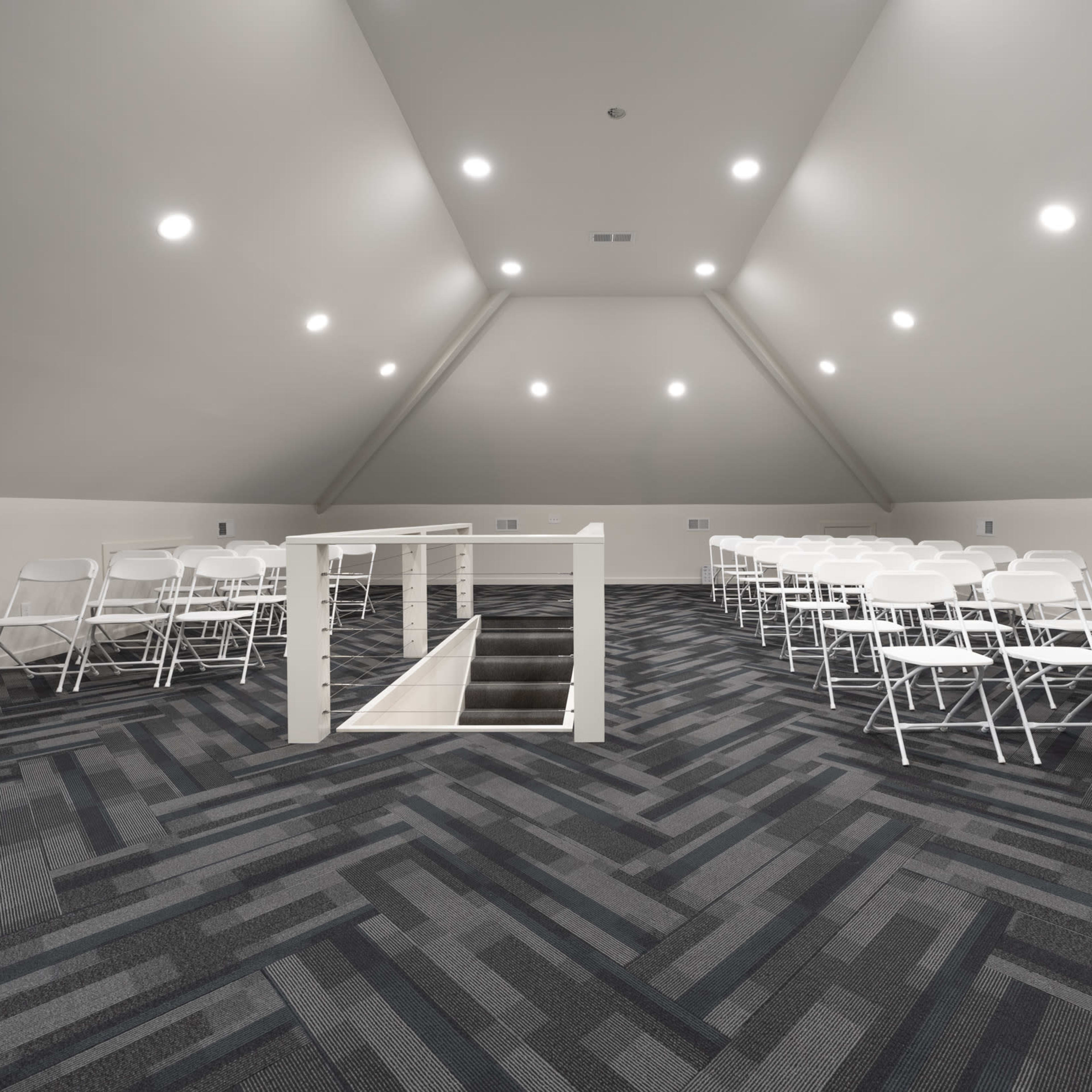 A spacious attic area with rows of white folding chairs arranged for an event, illuminated by recessed lighting.