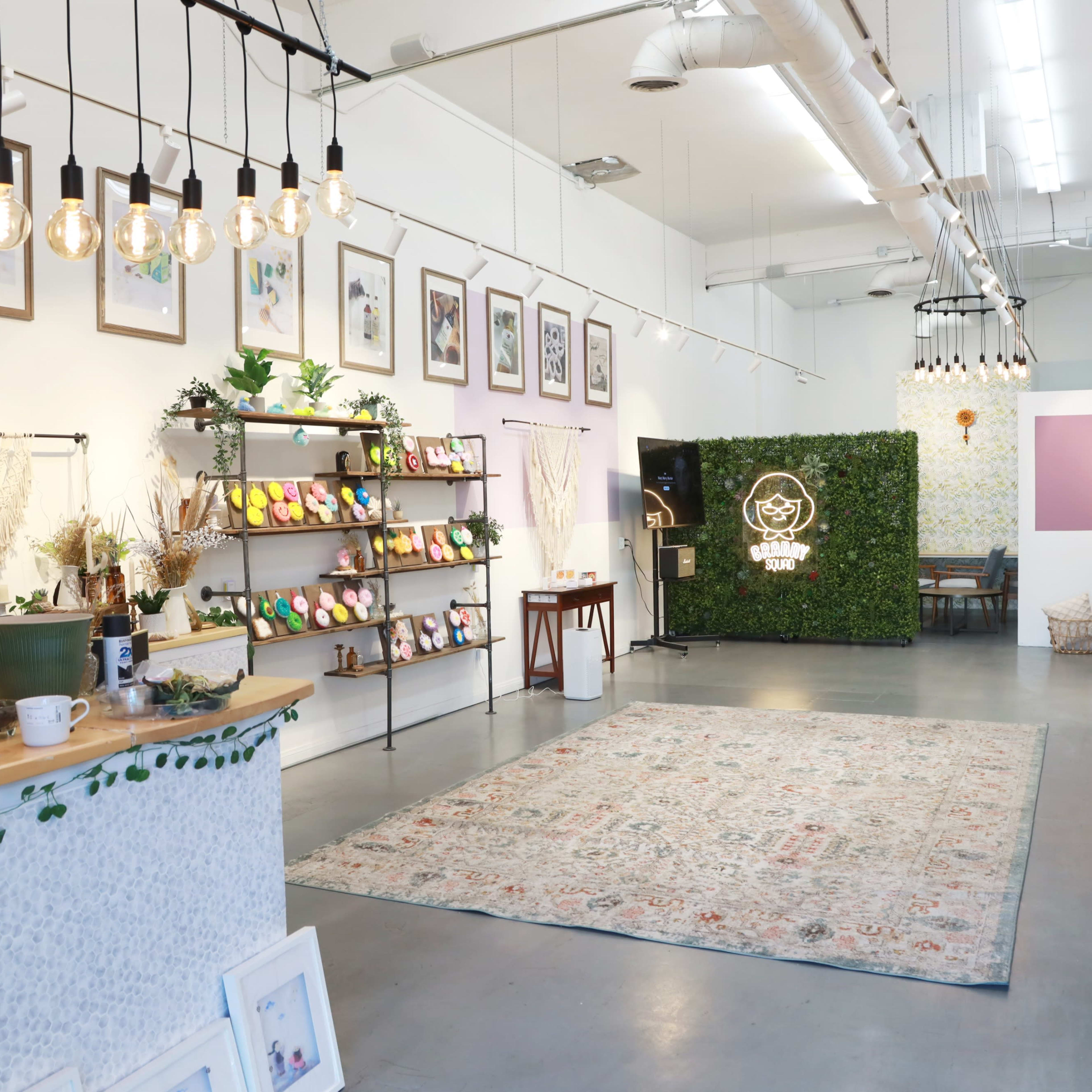A bright, modern shop interior with wooden shelving, plants, and decorative artwork on the walls.
