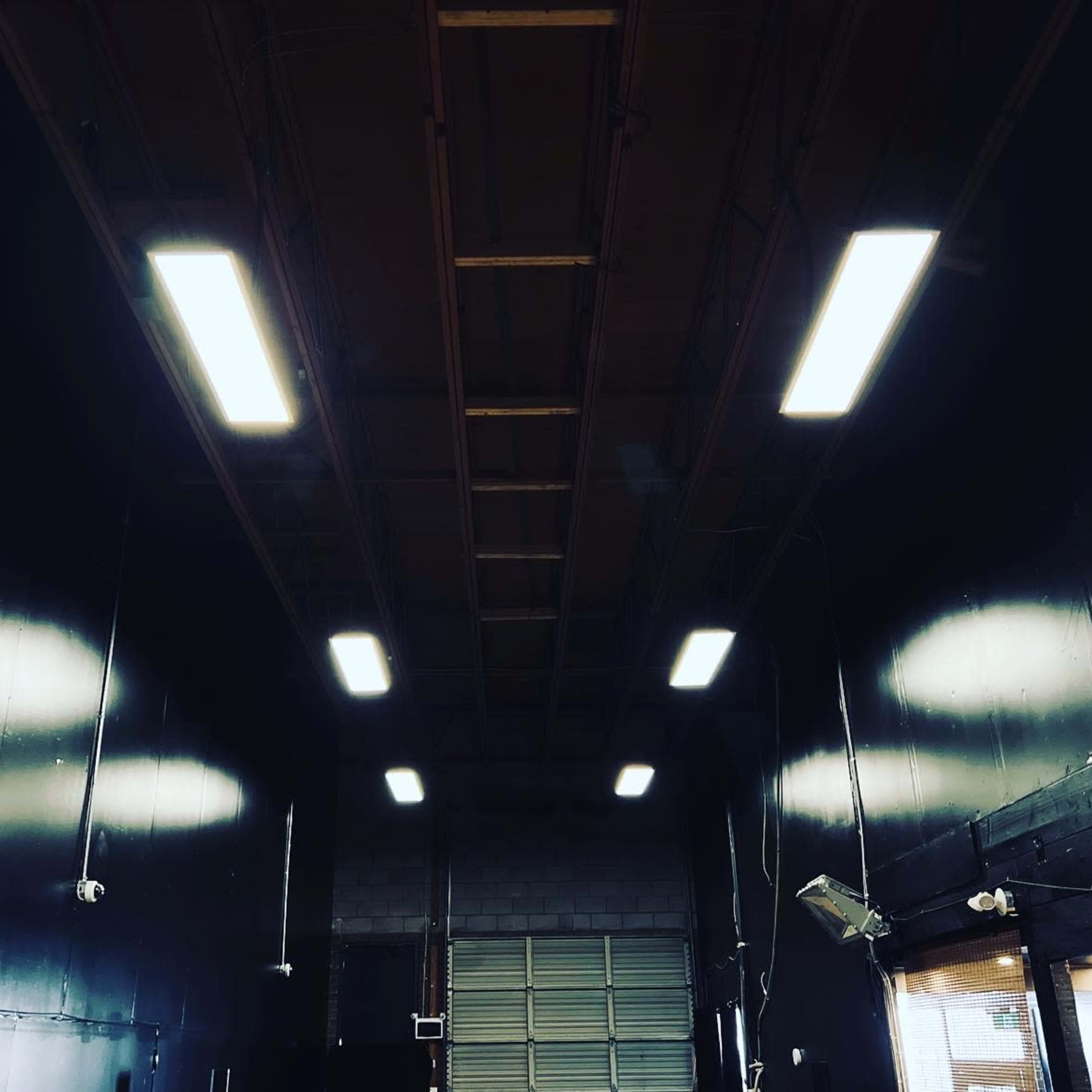 An industrial space with a high ceiling, illuminated by fluorescent lights, and dark walls.