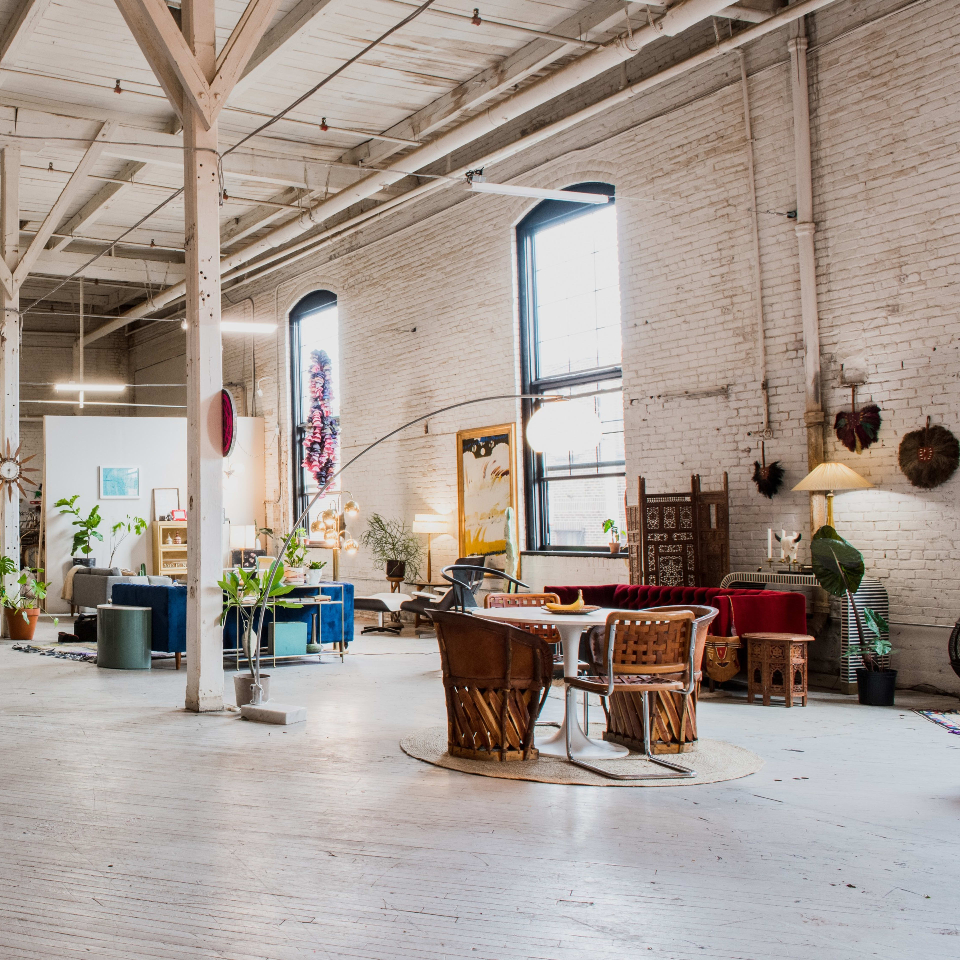 A spacious interior of a furniture store with white brick walls, various seating arrangements, and shelves displaying colorful textiles.