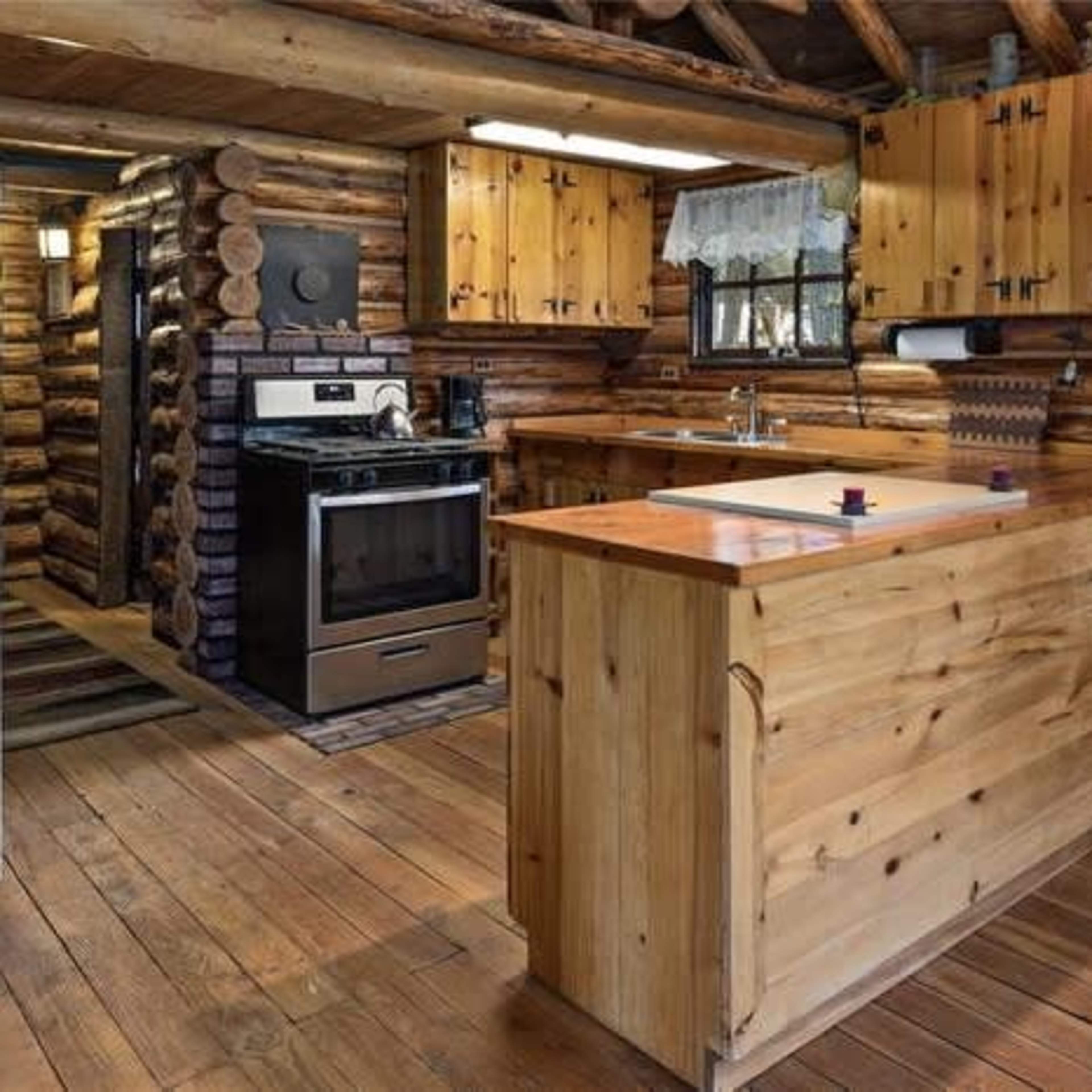 A rustic wooden kitchen with log cabin walls, a central island, and modern appliances.