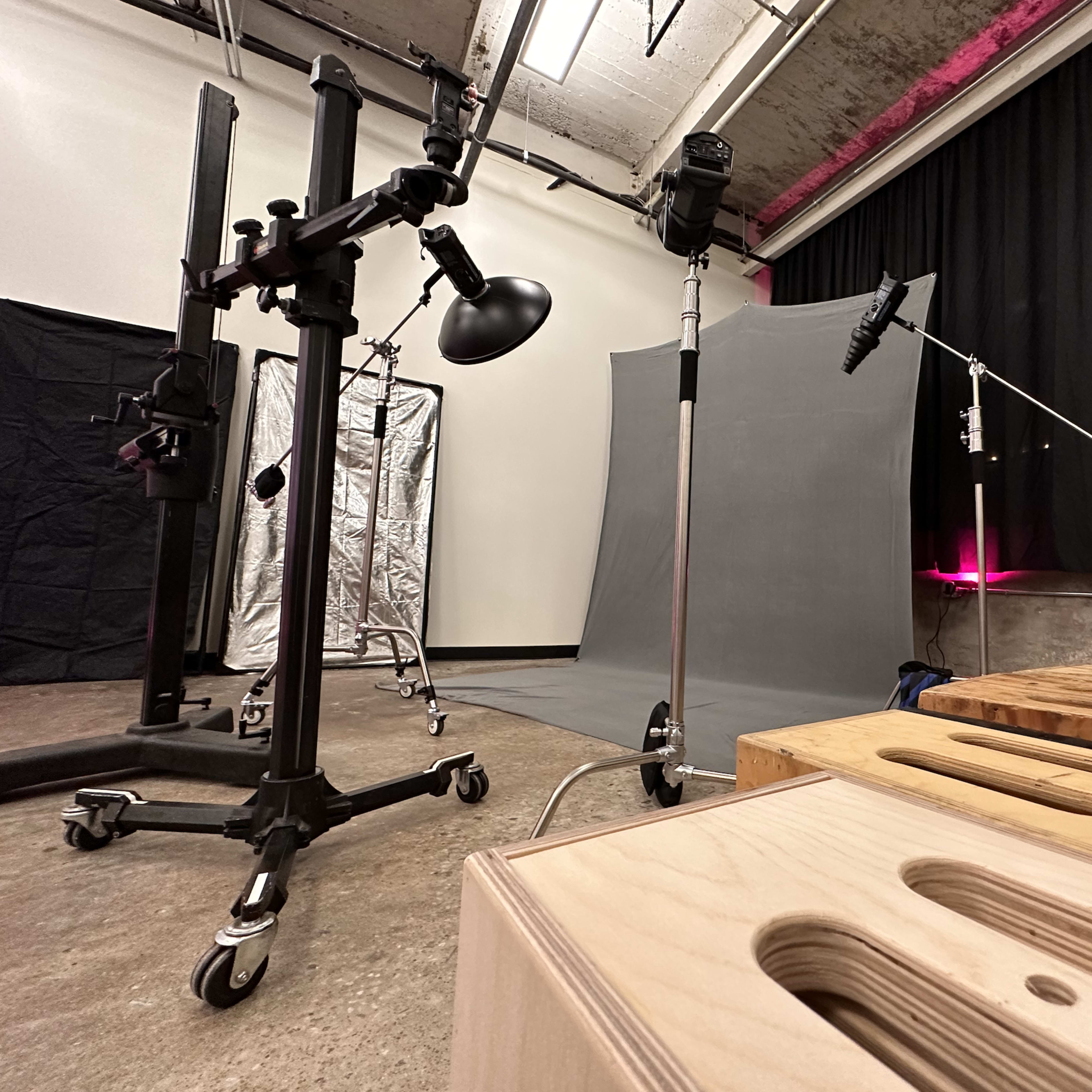 A photography studio setup with various equipment, including light stands, backdrops, and wooden blocks for support.