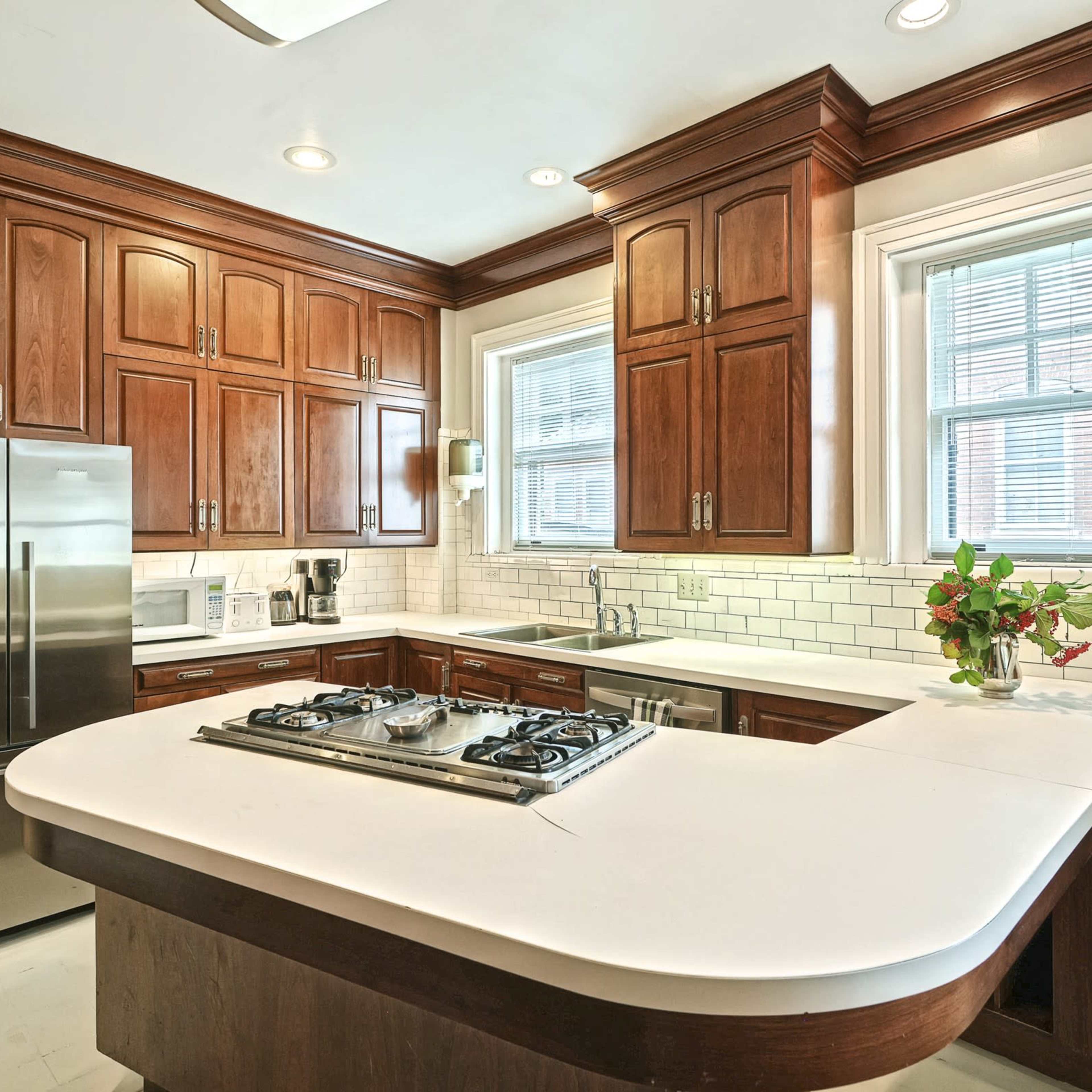 A modern kitchen featuring wooden cabinetry, stainless steel appliances, and a white countertop with a gas cooktop.