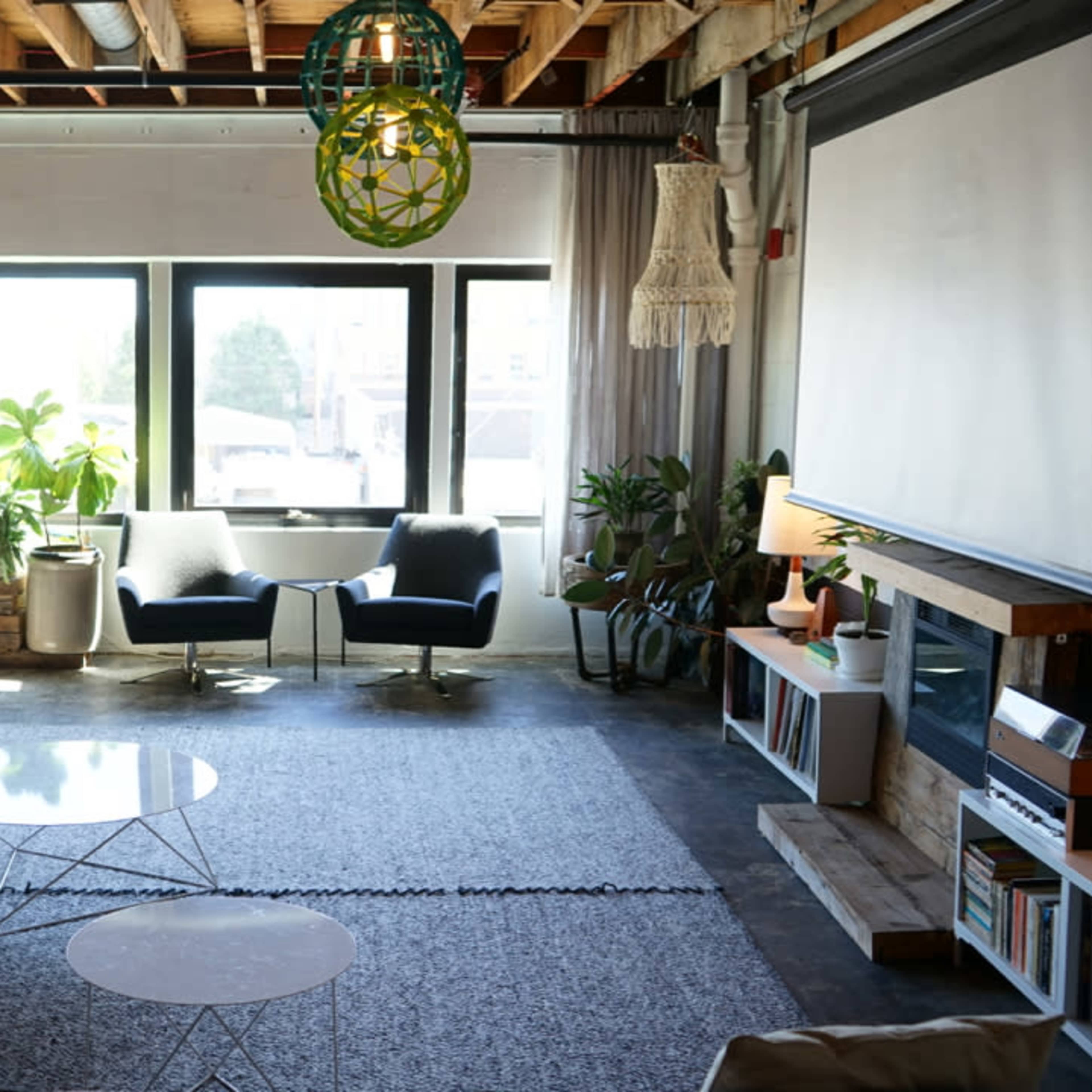 A modern living space with a gray sofa, two chairs, a round coffee table, and large windows that let in natural light.