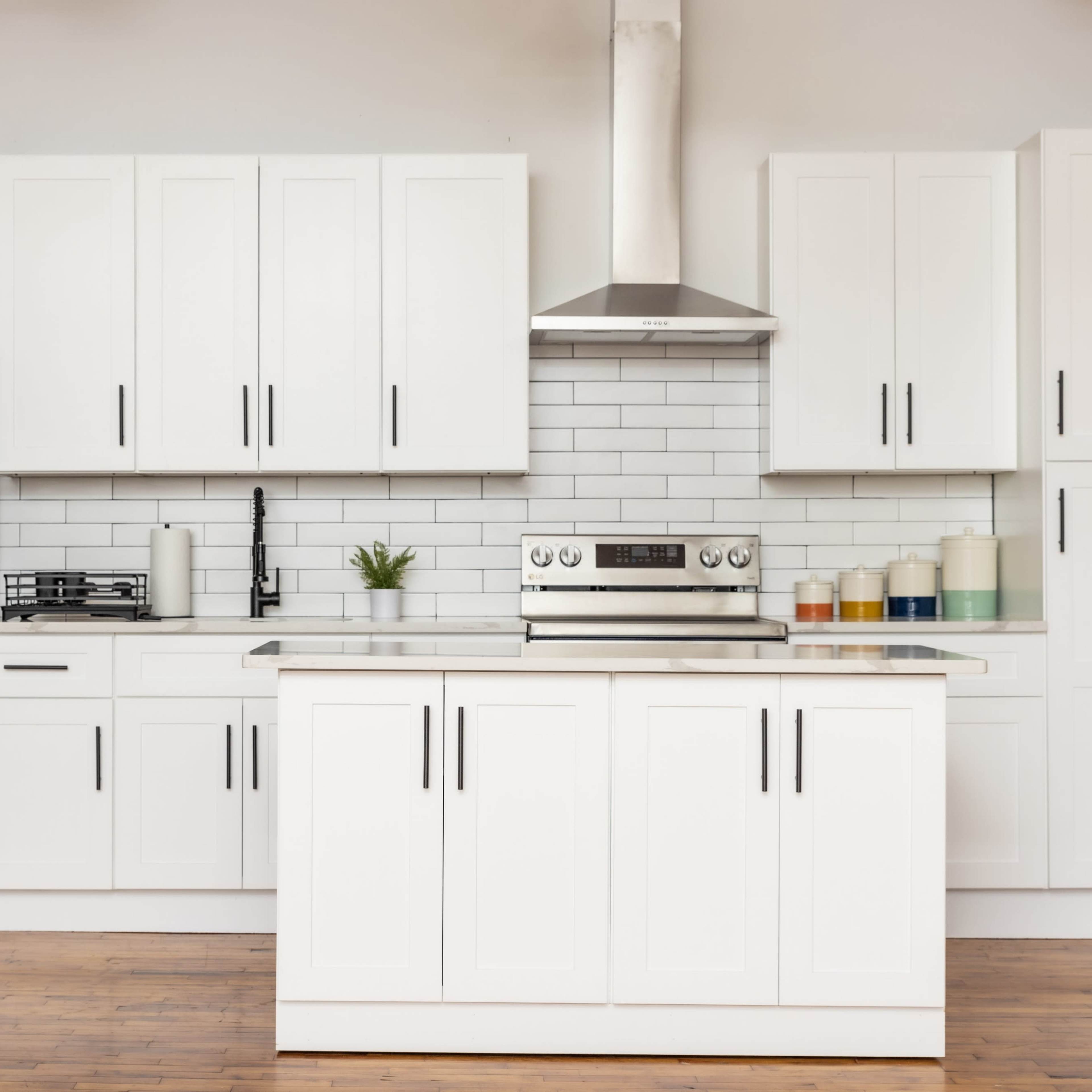 A modern kitchen features white cabinets, stainless steel appliances, a gas stove, and a central island with a polished surface.