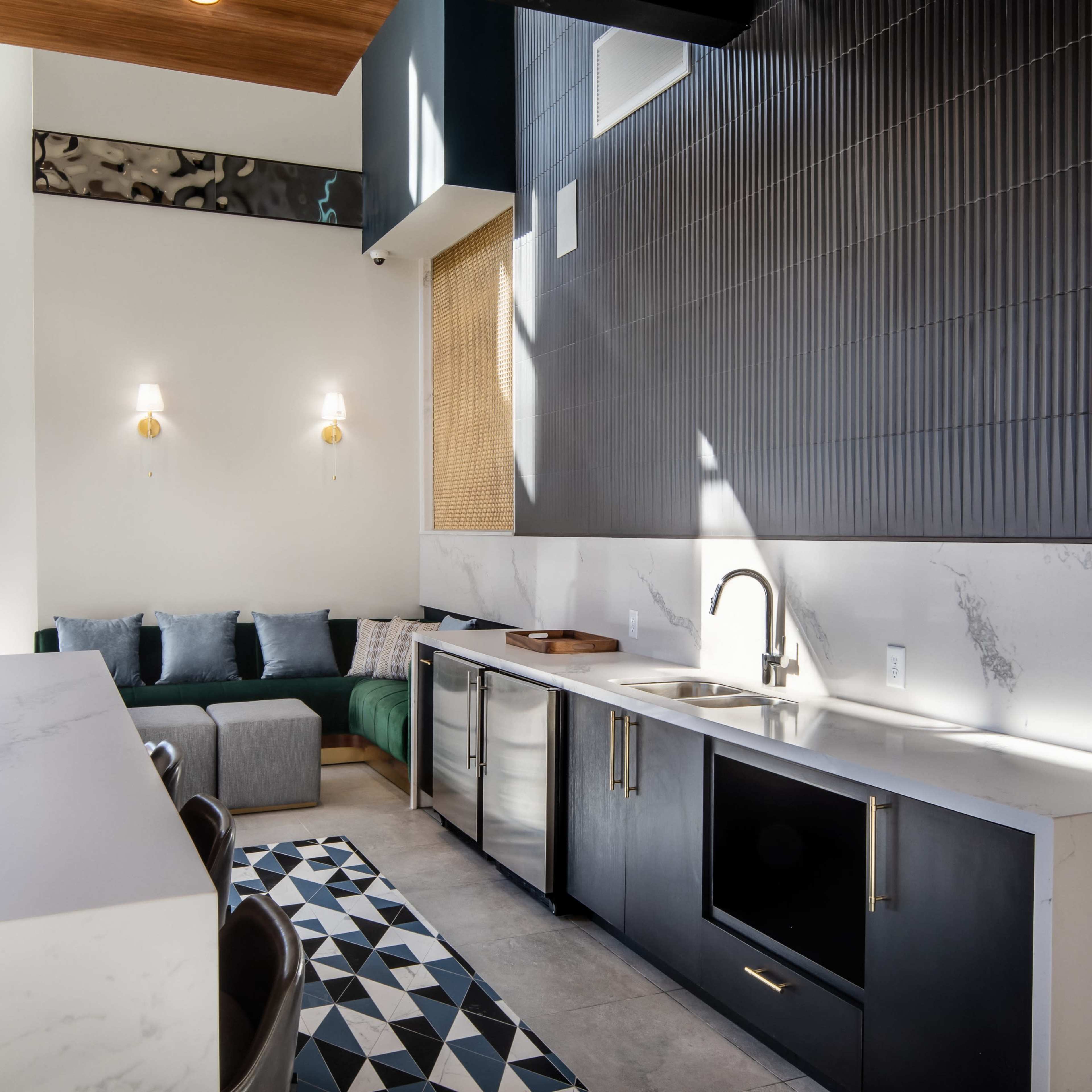 A modern kitchen setup with a black and white color scheme, featuring marble countertops, a sink, and a geometric-patterned rug.