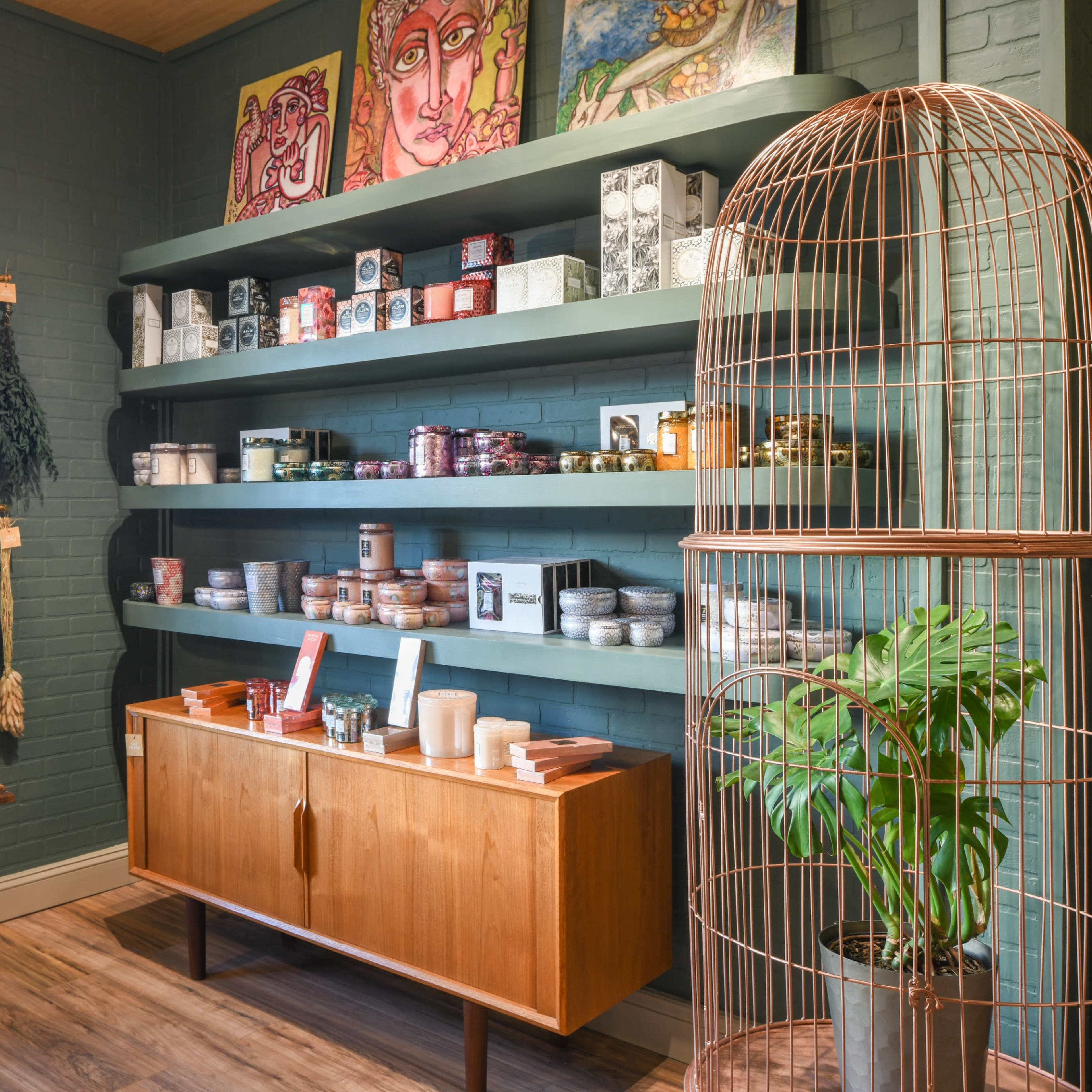 A well-organized interior of a shop with shelves displaying various jars and products, a wooden table, and decorative items including plants and artwork.