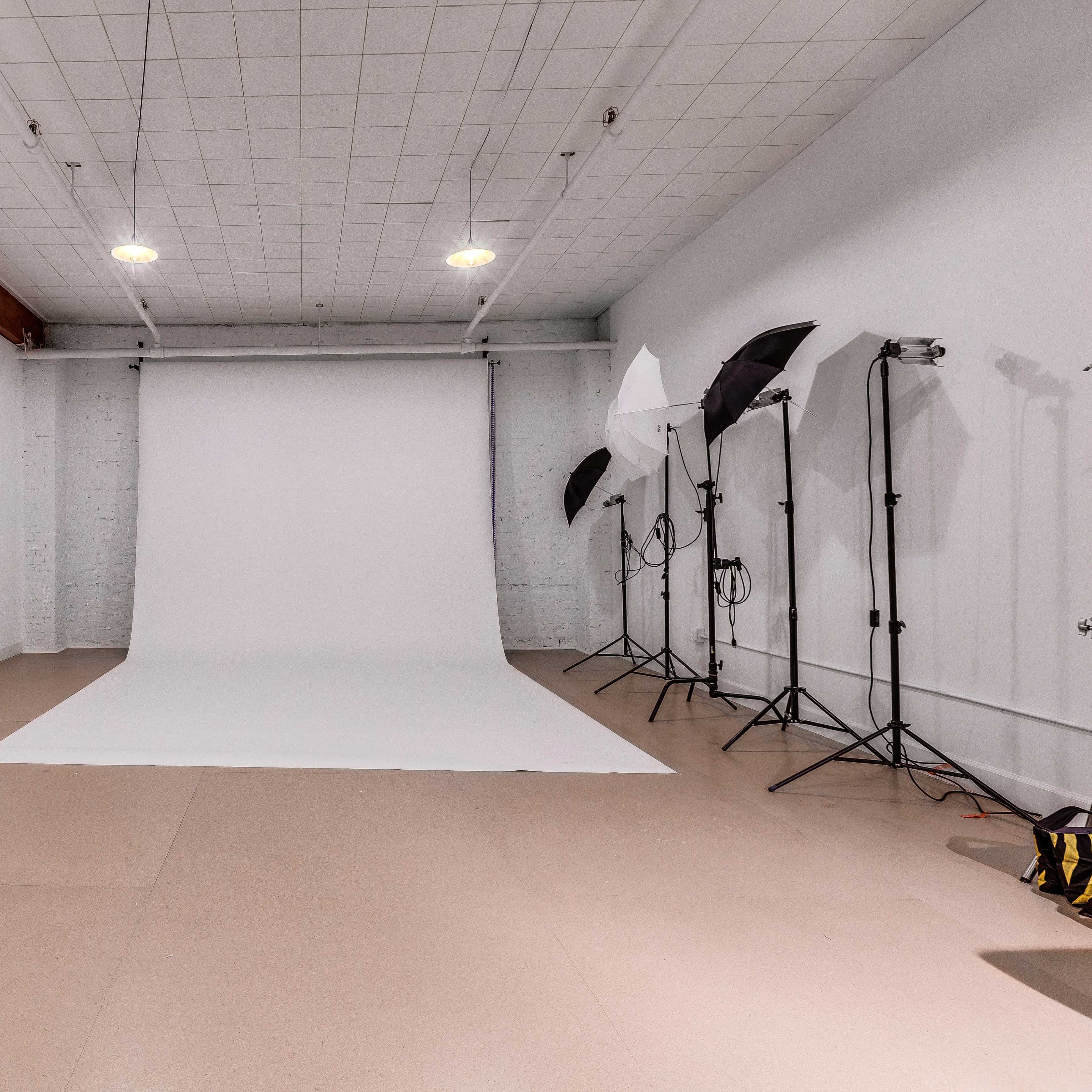 A photography studio featuring a white backdrop, softbox lights, and a clean, minimalist interior.