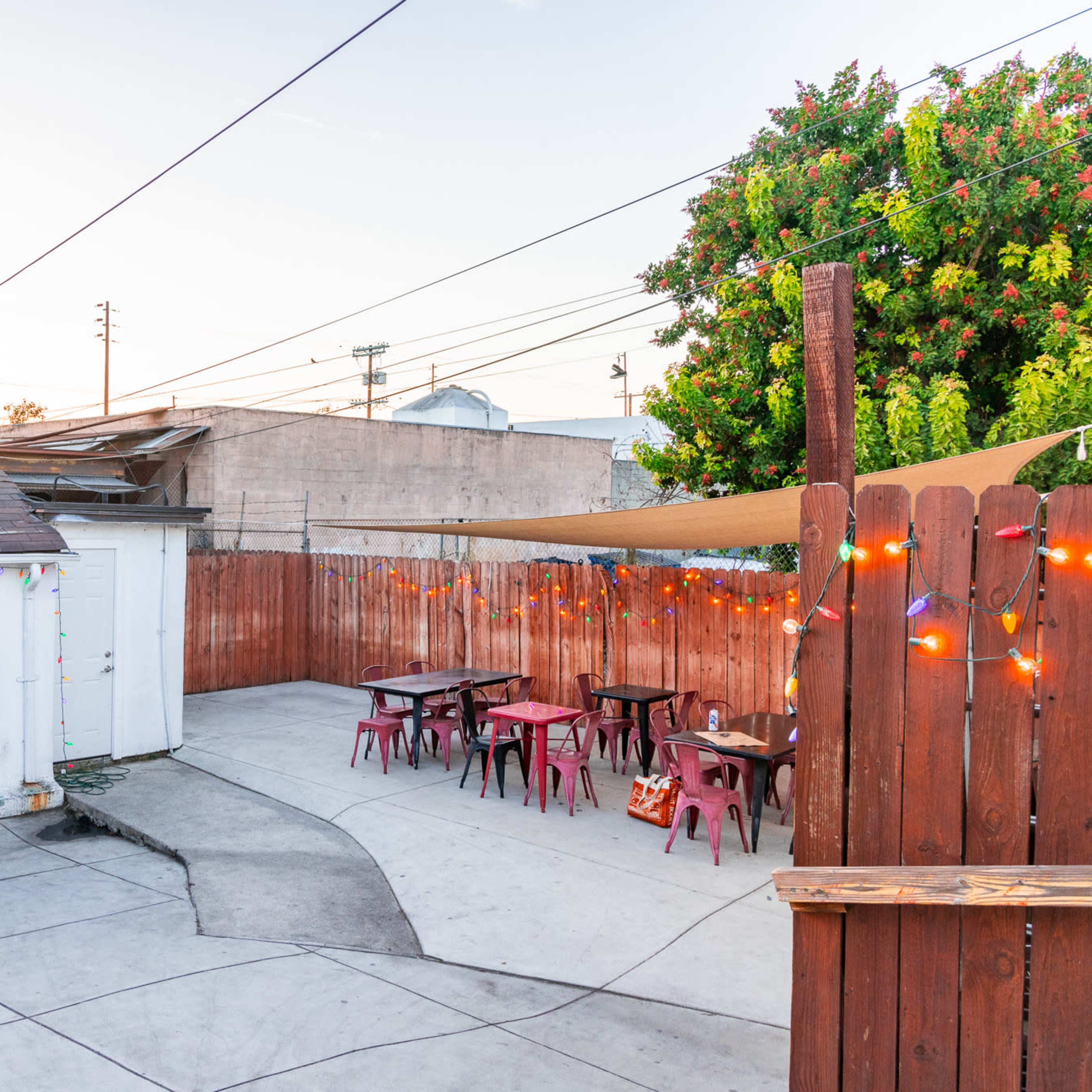 An outdoor patio area with tables and chairs, a small building labeled "Permanent Records," and string lights illuminating the space.
