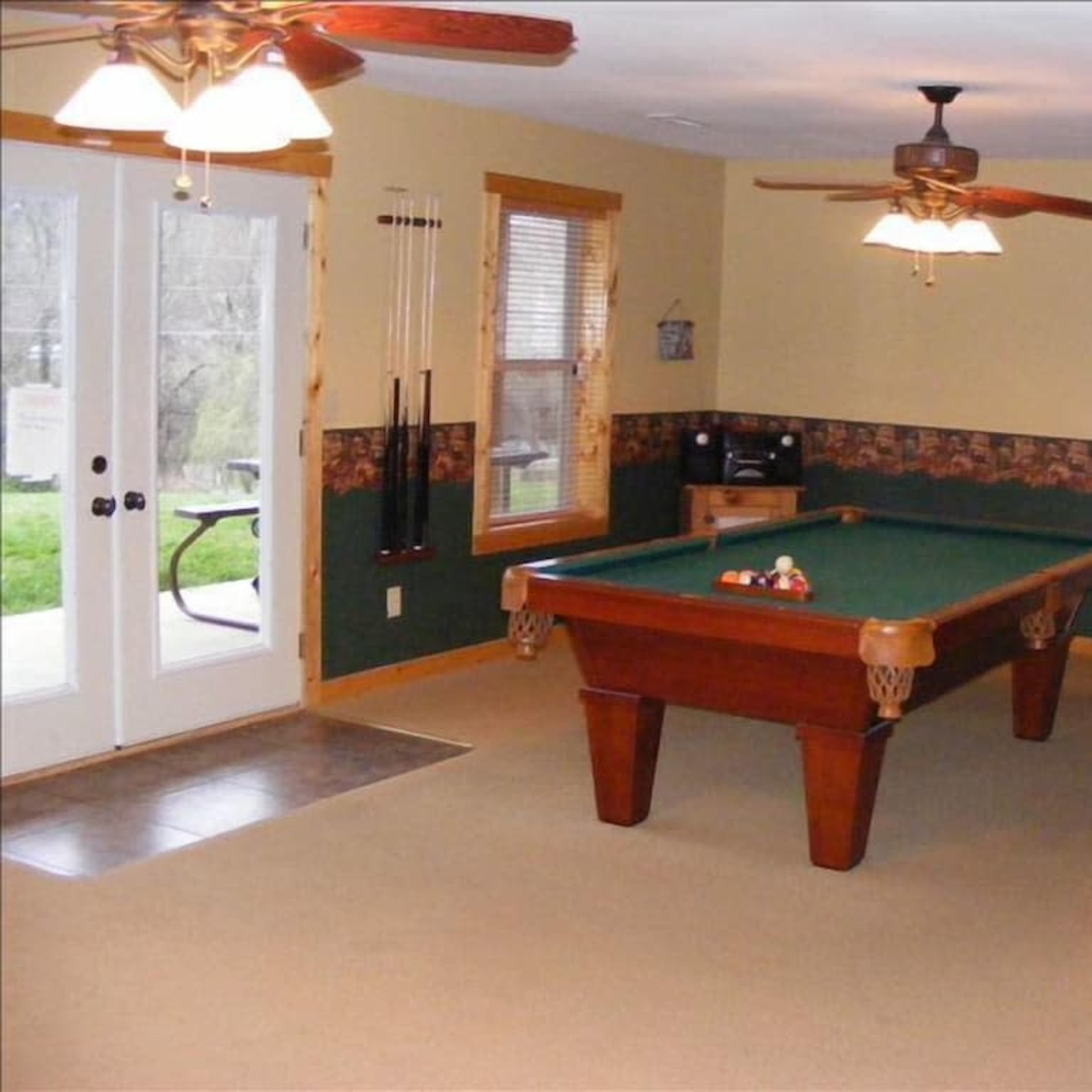 A game room featuring a pool table, bar stools, and large double doors leading to an outdoor area.