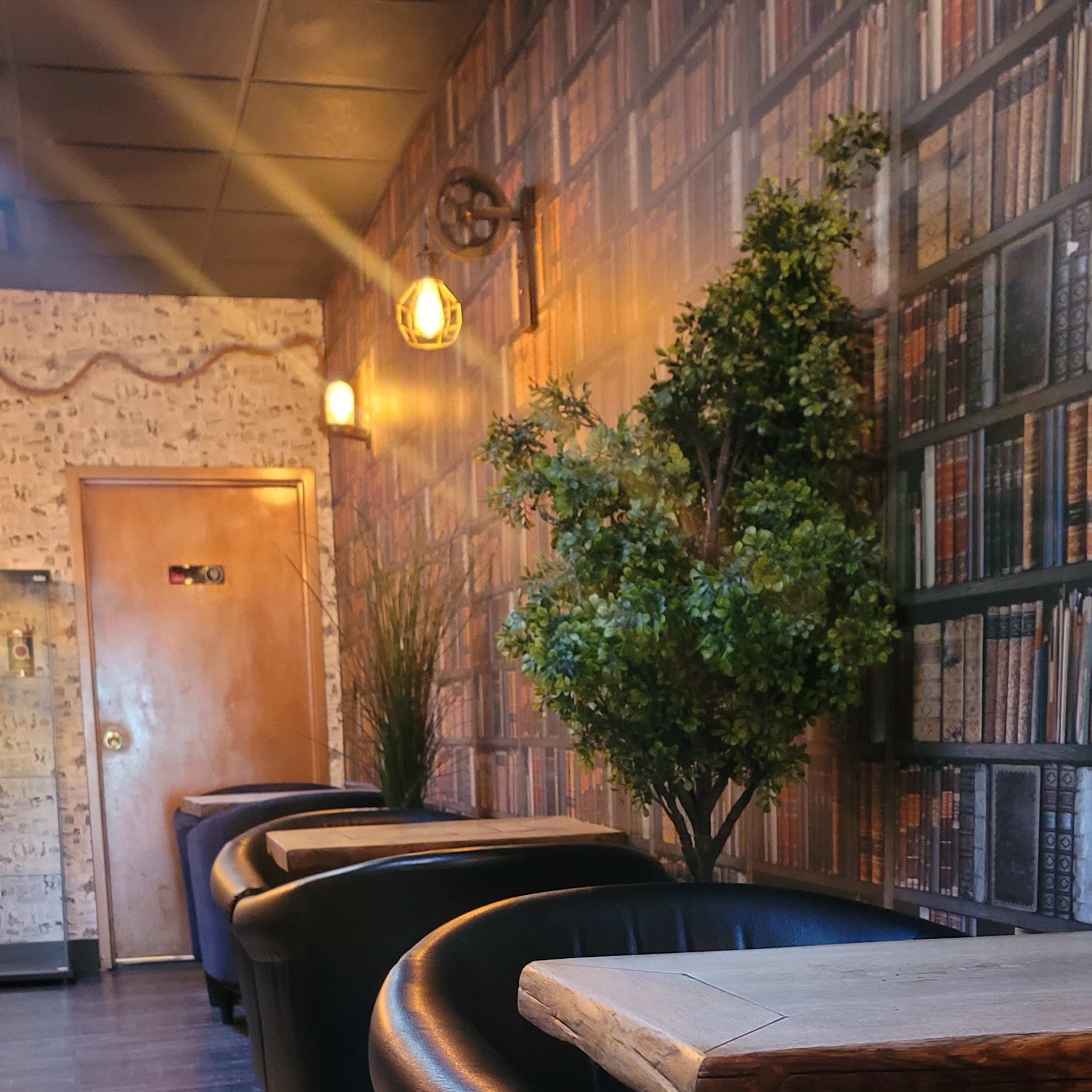 A narrow hallway lined with black seating and a wall decorated with a bookshelf design.