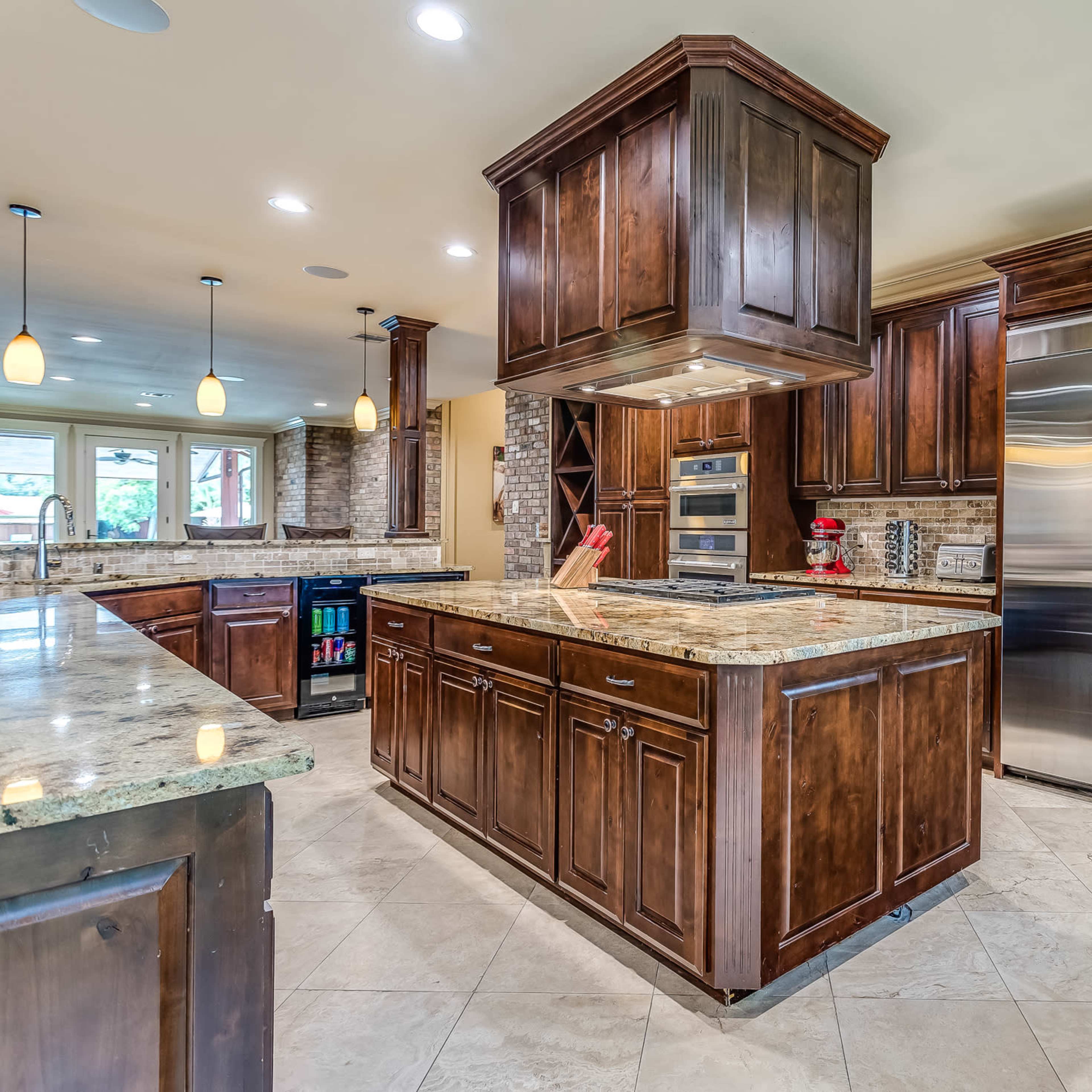 A spacious kitchen with dark wood cabinetry, a central island, and stainless steel appliances.
