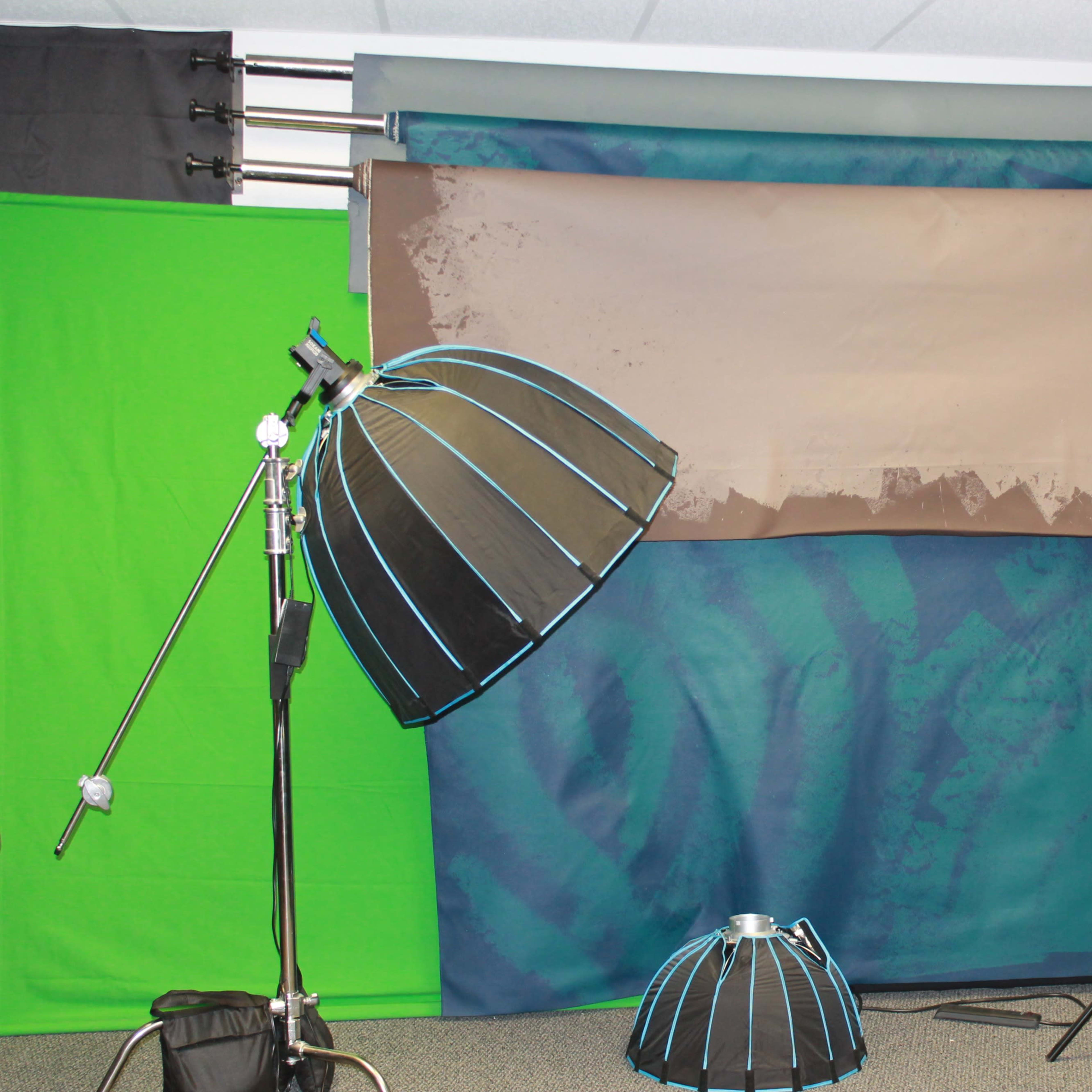 A photography studio setup with various backdrops, lighting equipment, and reflectors arranged in the space.
