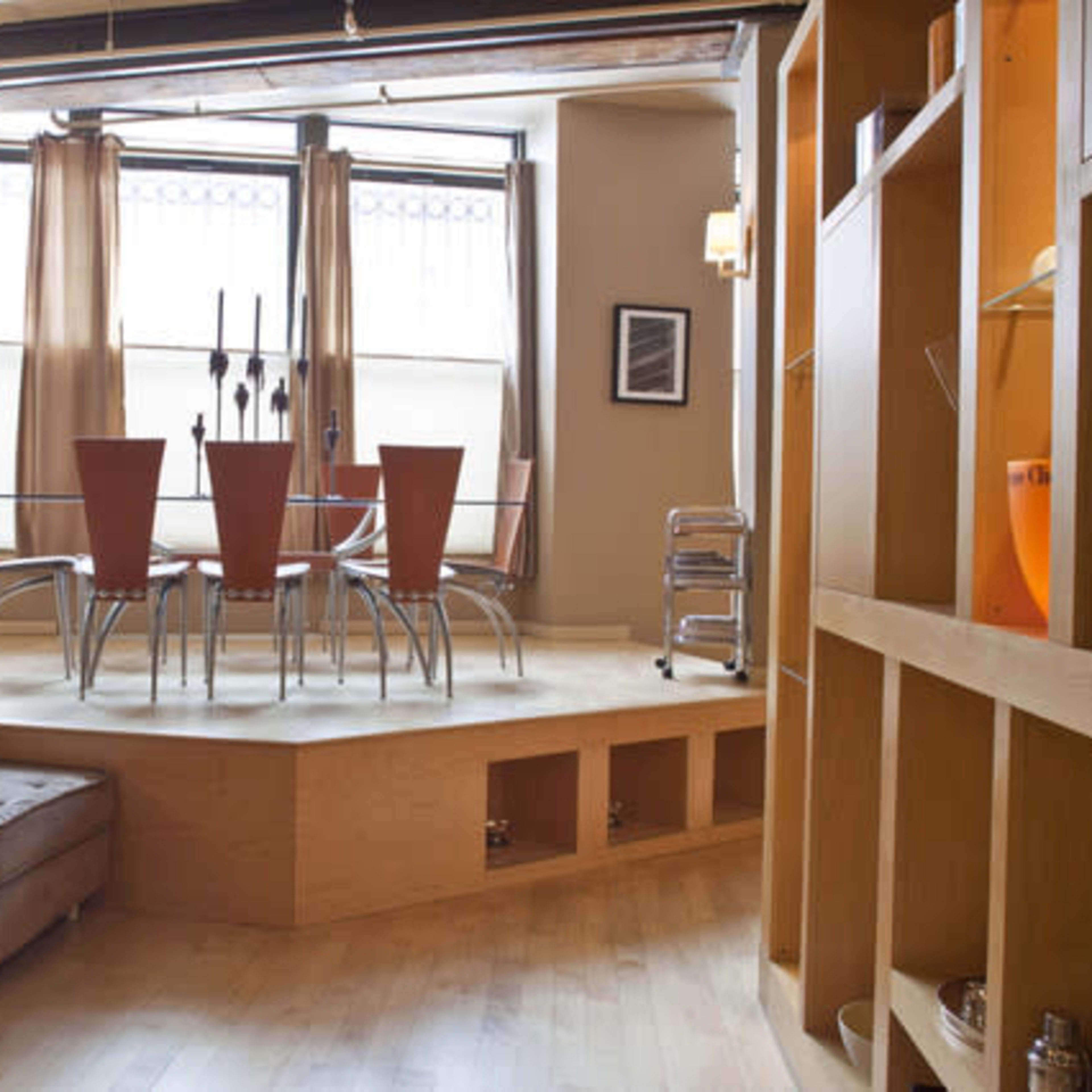 A modern living space featuring a sectional sofa, a glass coffee table, and a dining area with a round table and four chairs near large windows.