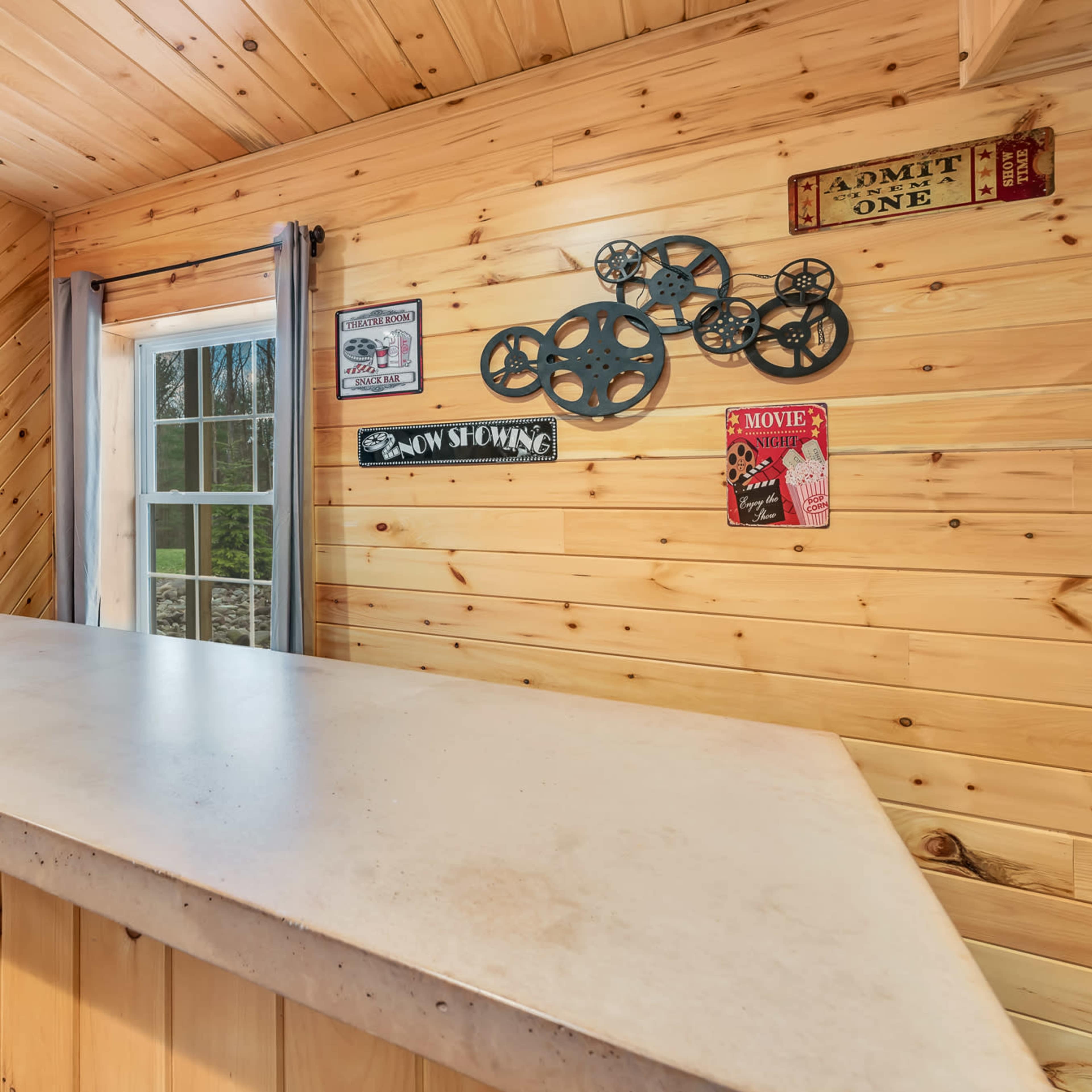 A wooden bar area with a concrete countertop, featuring vintage movie-themed decorations on the walls.
