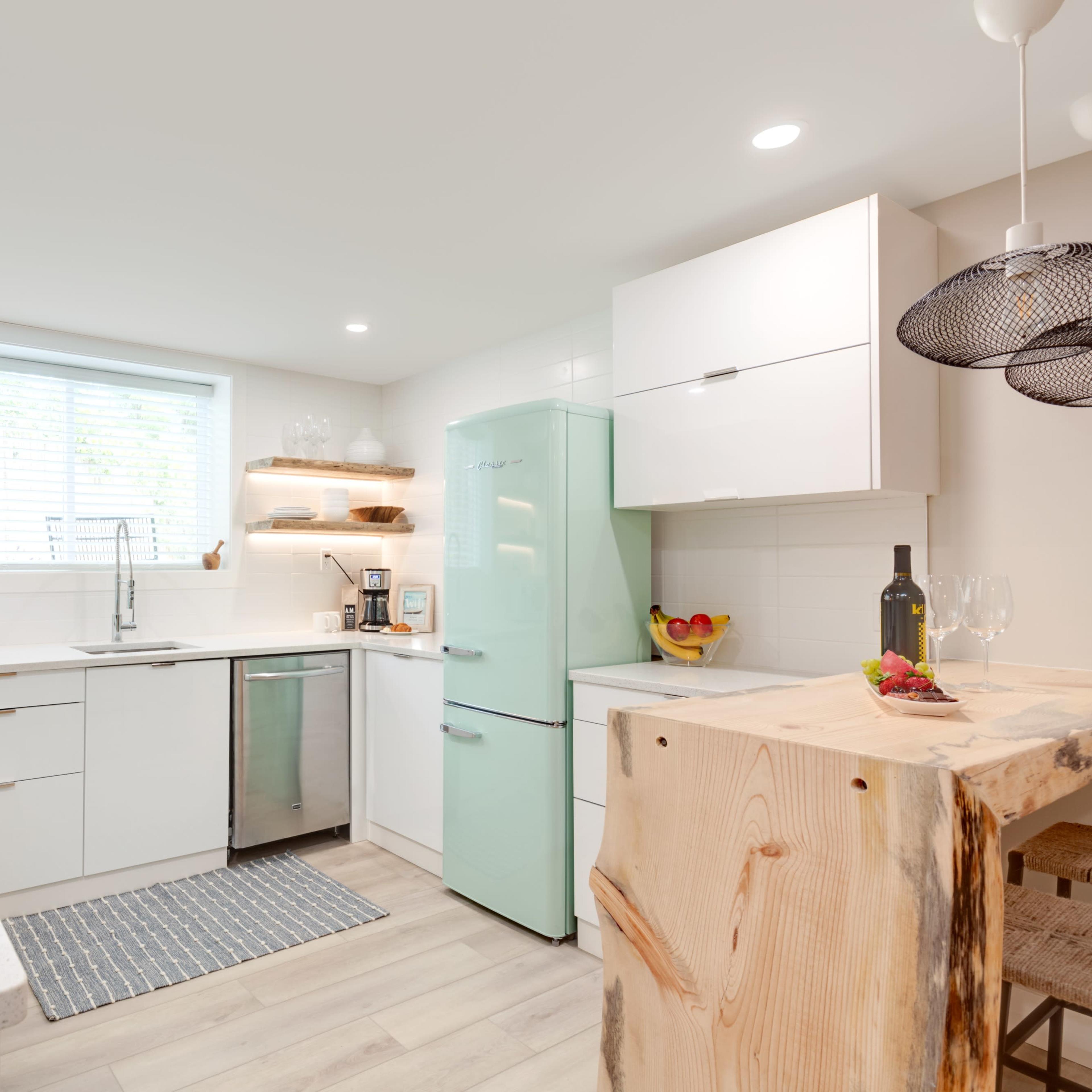 The kitchen features white cabinetry, a mint green refrigerator, and wooden open shelves above a countertop.