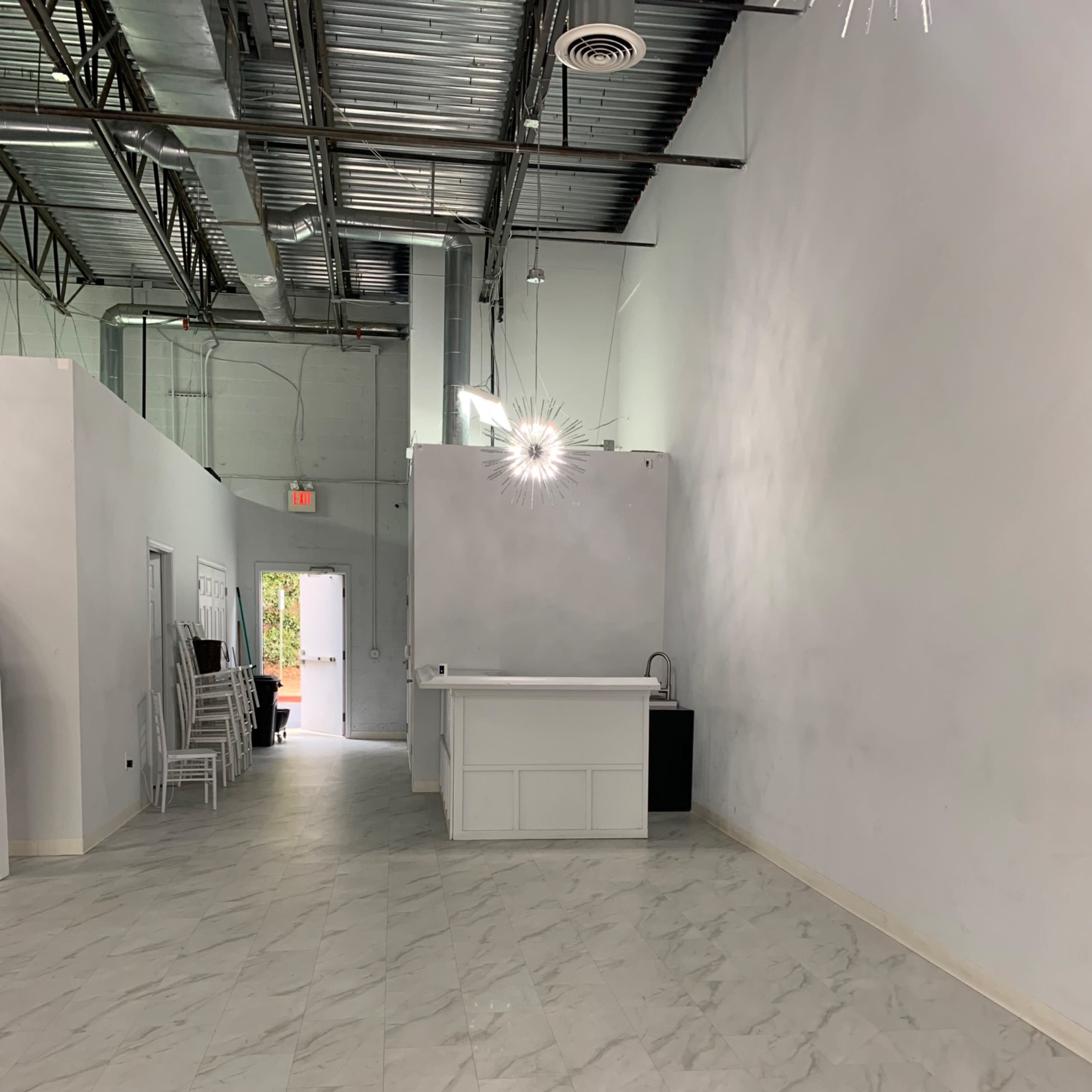 A spacious, empty interior with light-colored walls, tile flooring, and a reception area at one end.