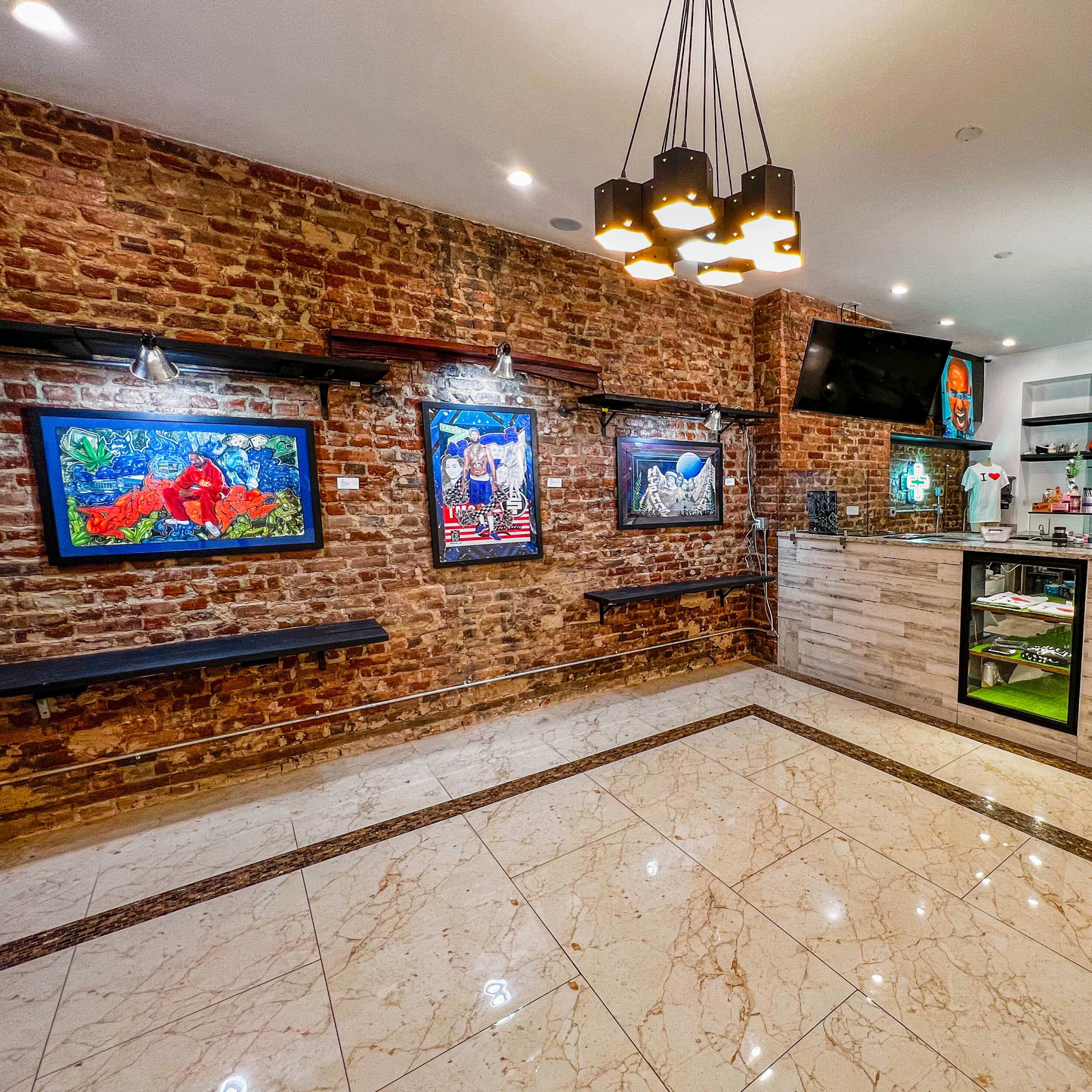 An interior of a modern gallery or shop featuring exposed brick walls, framed artwork, and a display counter with glass cases.