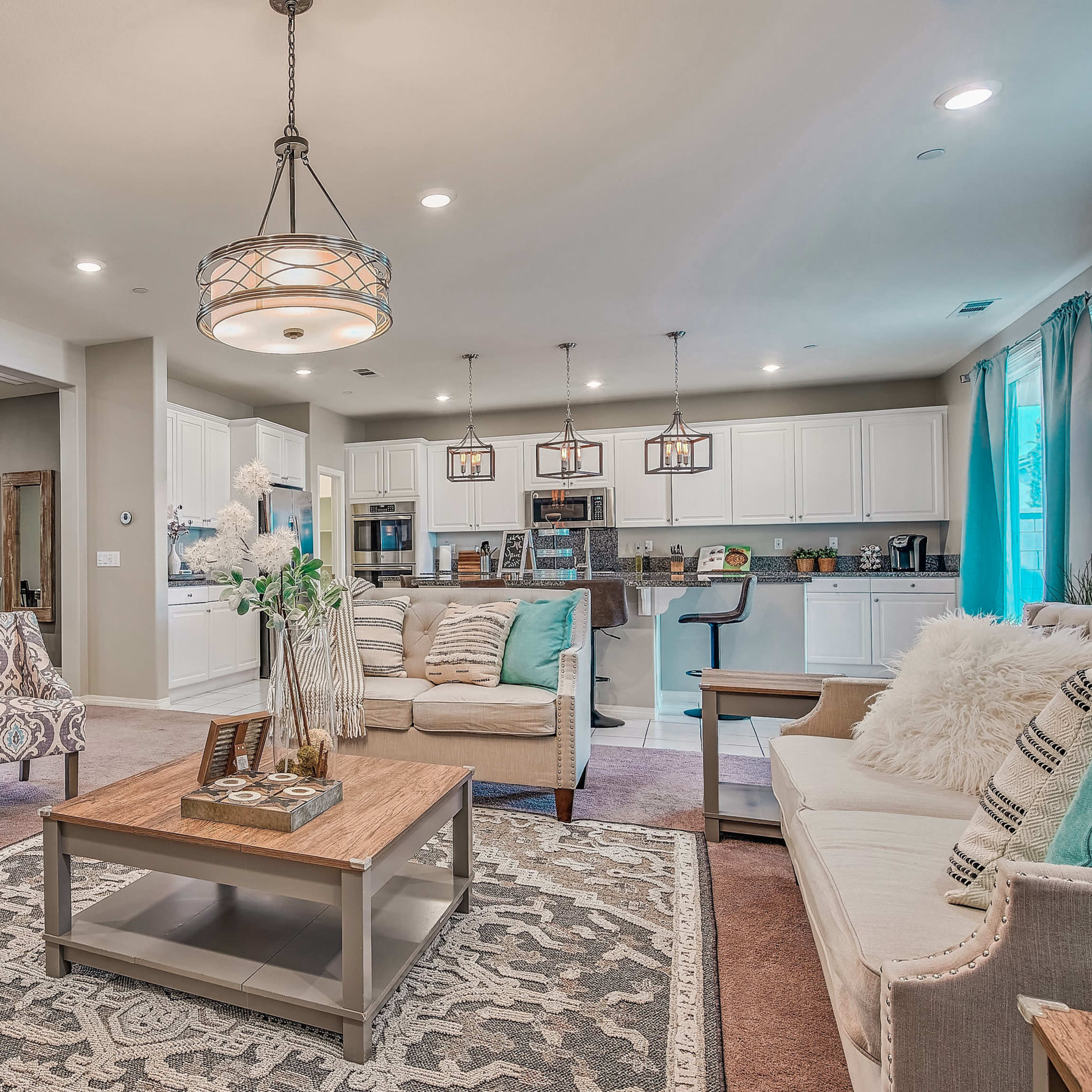 A modern living room with a dining area, featuring patterned chairs, a coffee table, and an open kitchen in the background.