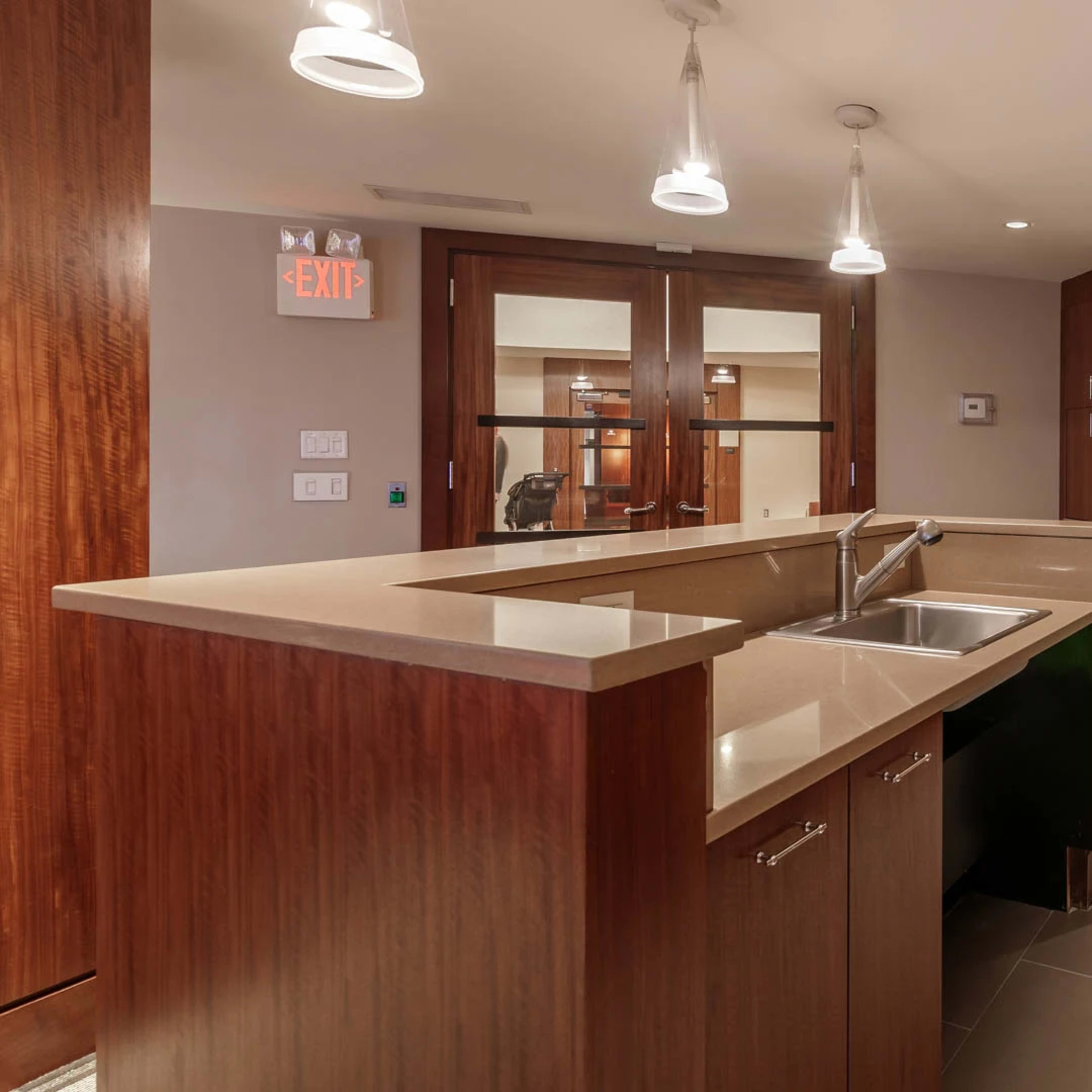 A modern kitchen with wooden cabinetry, a stainless steel microwave, and stone countertops.