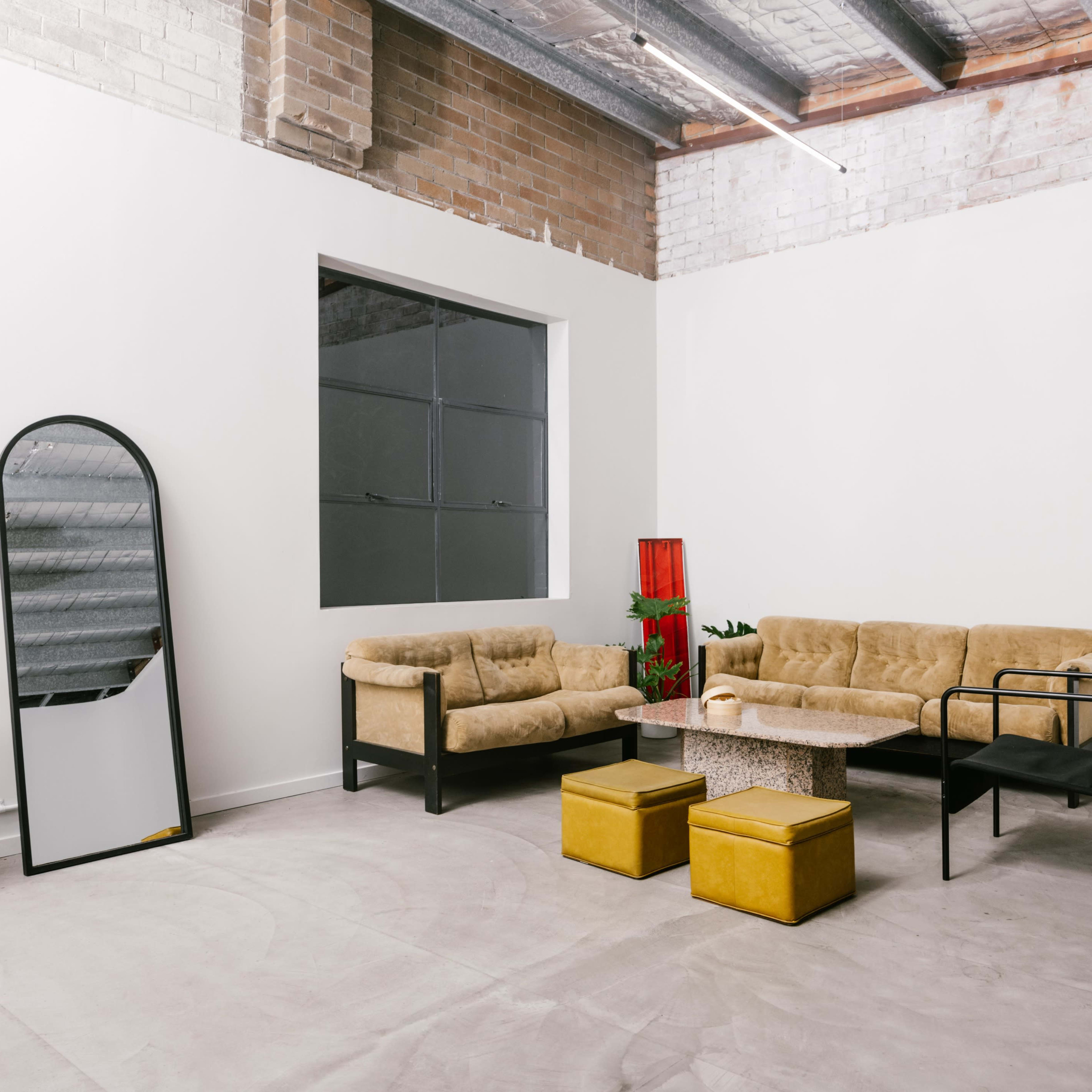 A minimalist living space with two sofas, a chair, a coffee table, and a mirror against a white wall.