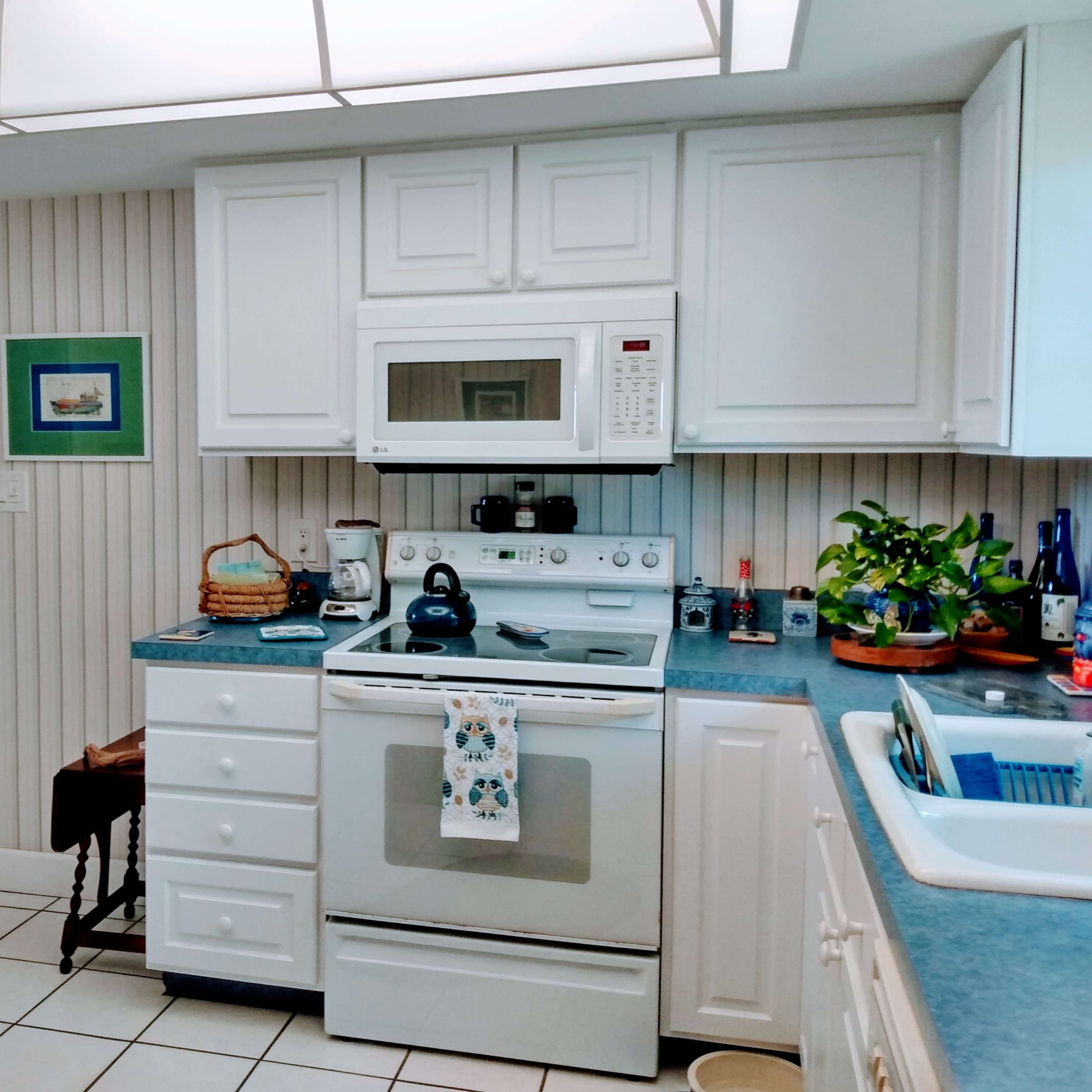 A bright kitchen with white cabinetry, a blue countertop, and various kitchen appliances arranged neatly.