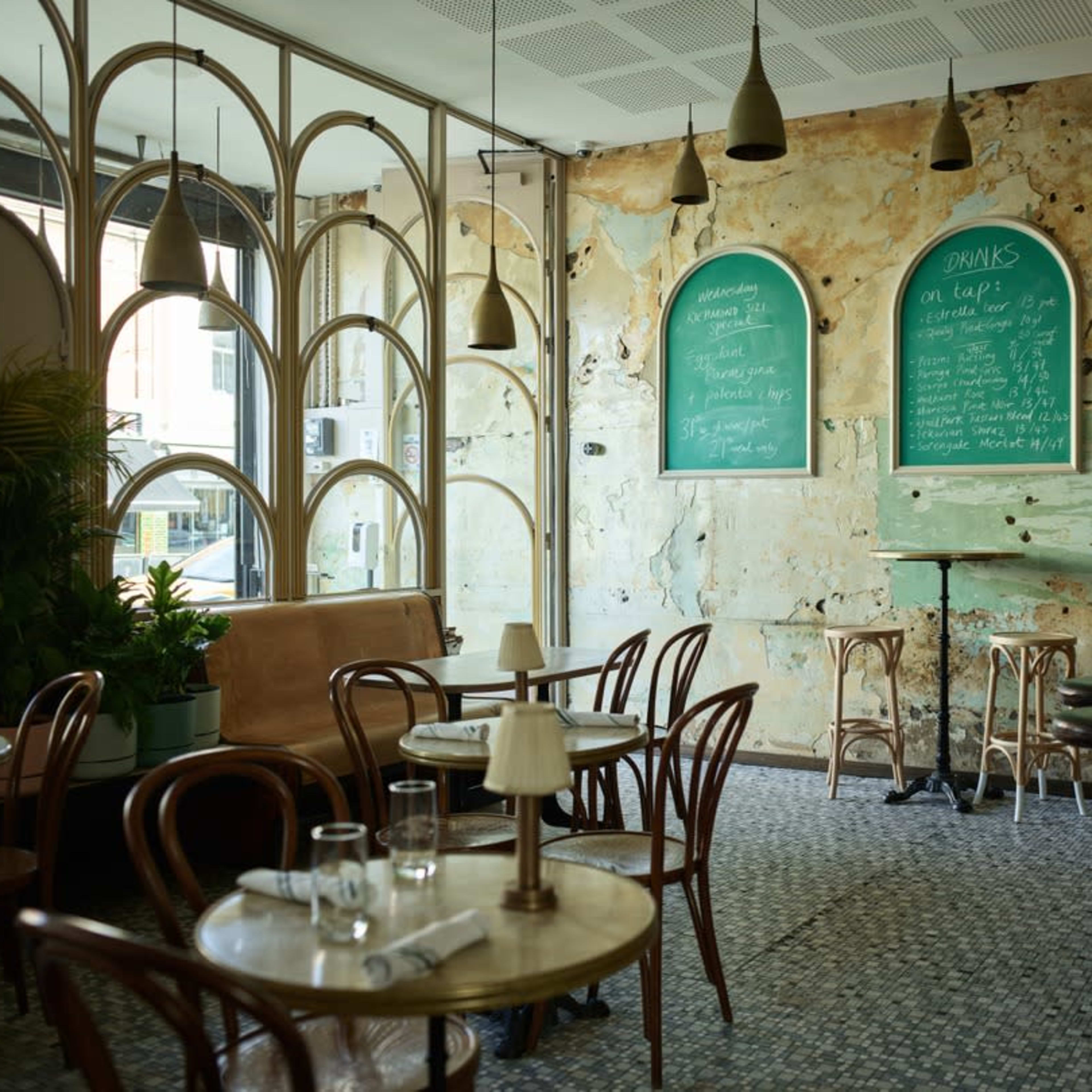 A cozy café with rustic décor, featuring wooden tables, a bar, and chalkboard menus on the walls.