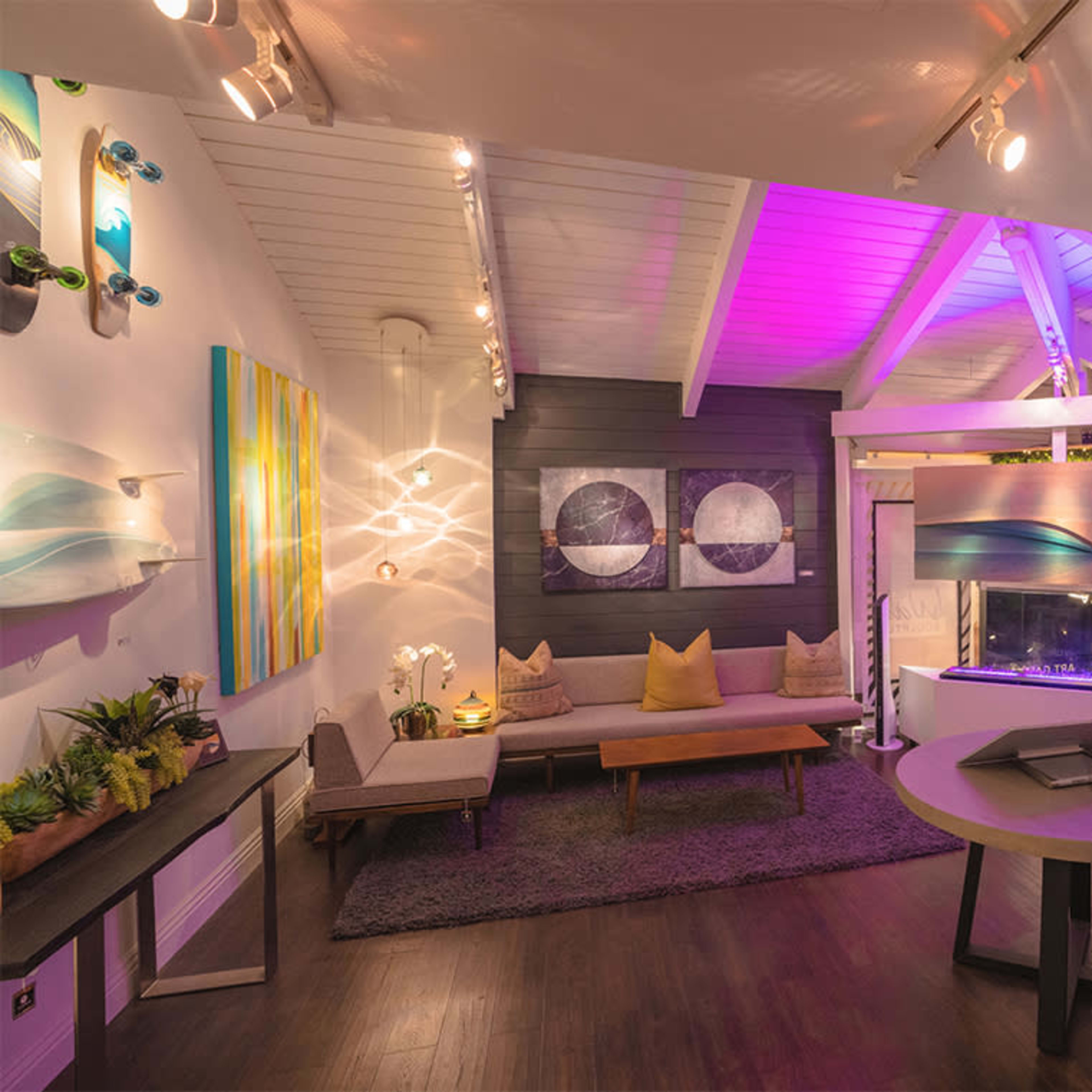A modern indoor space with artwork on the walls, a cozy seating area, and vibrant lighting.