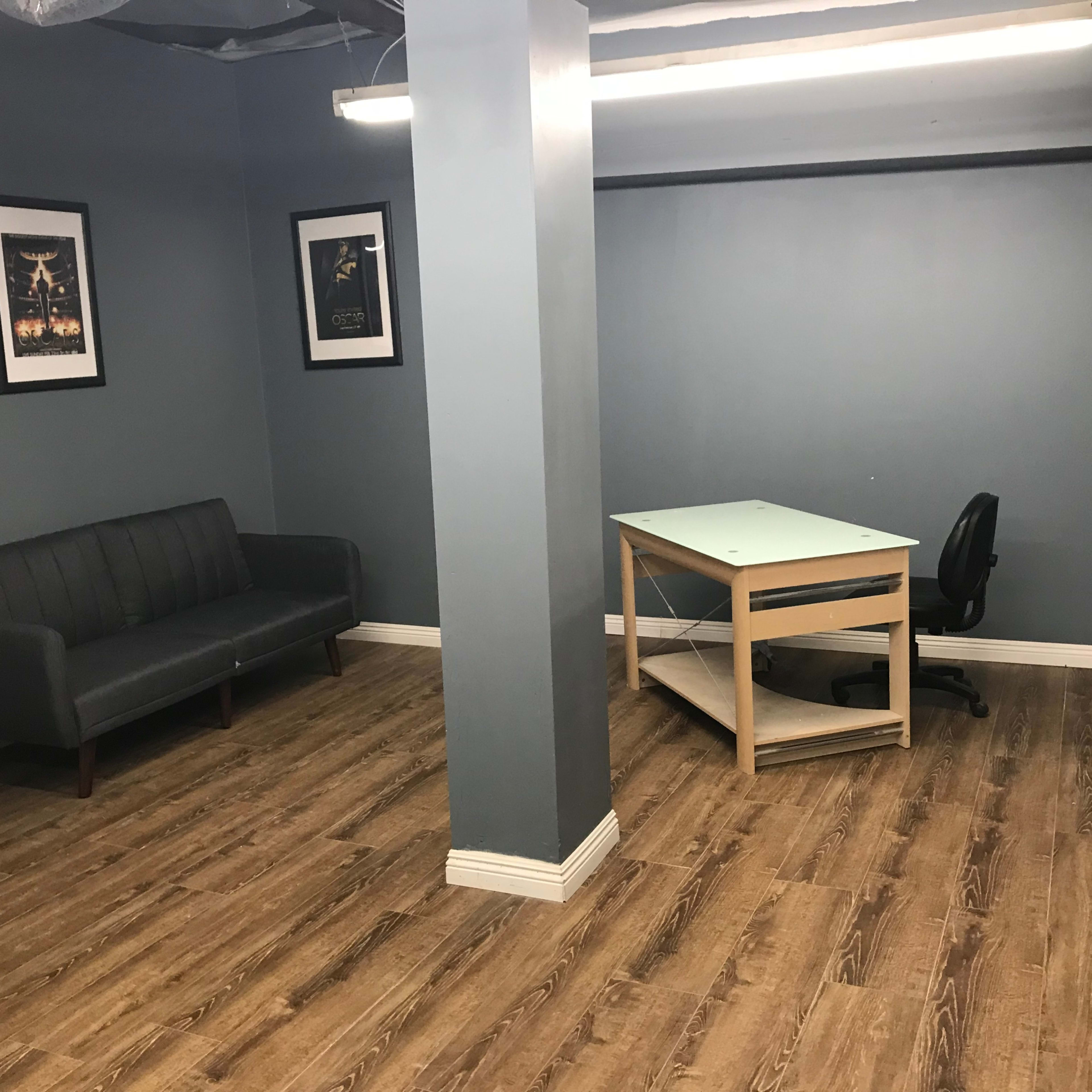 A sparse room with a dark blue wall, a couch on one side, and a desk with a chair on the other.