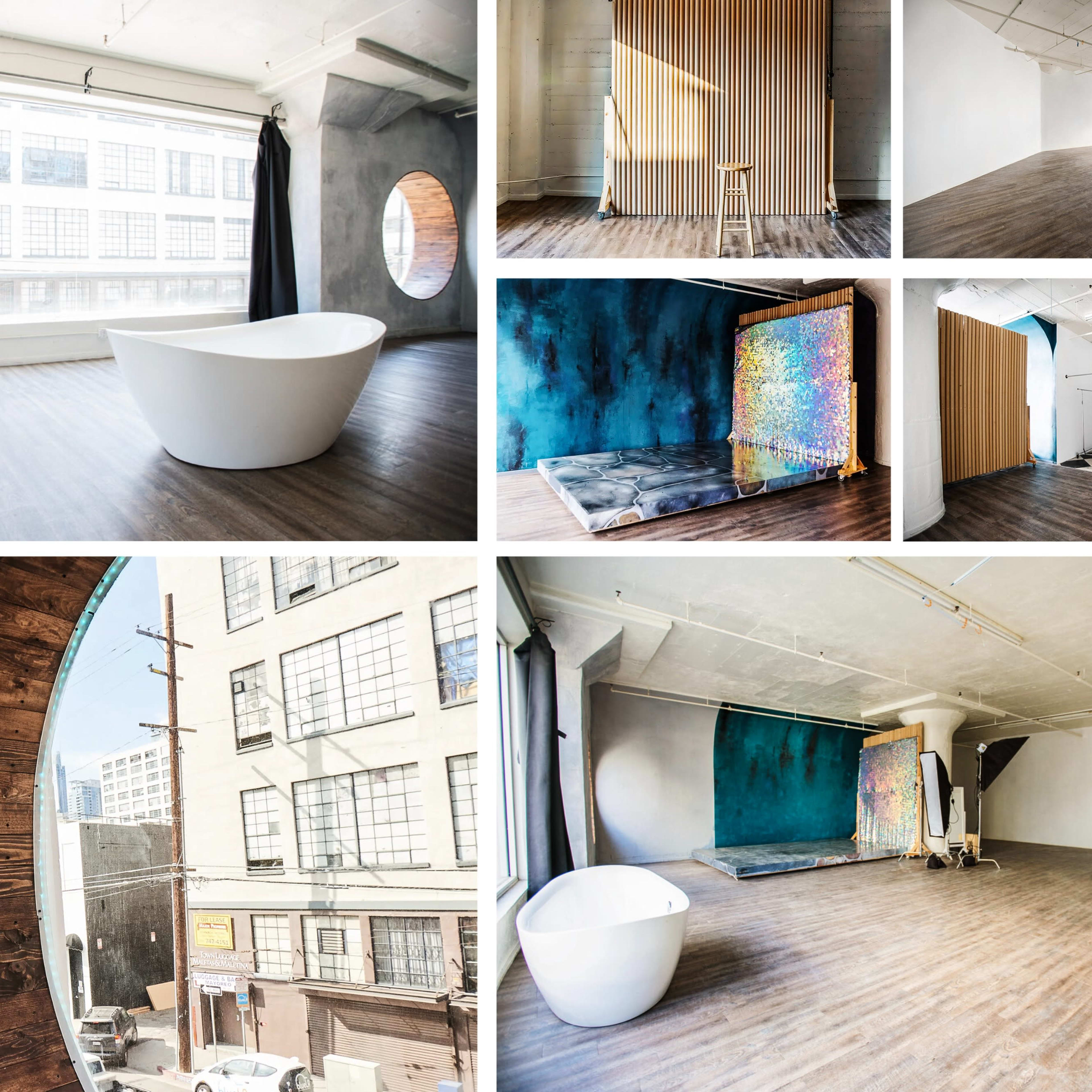 A modern, minimalist studio space featuring a white freestanding bathtub, large windows, wooden accents, and various textured walls.