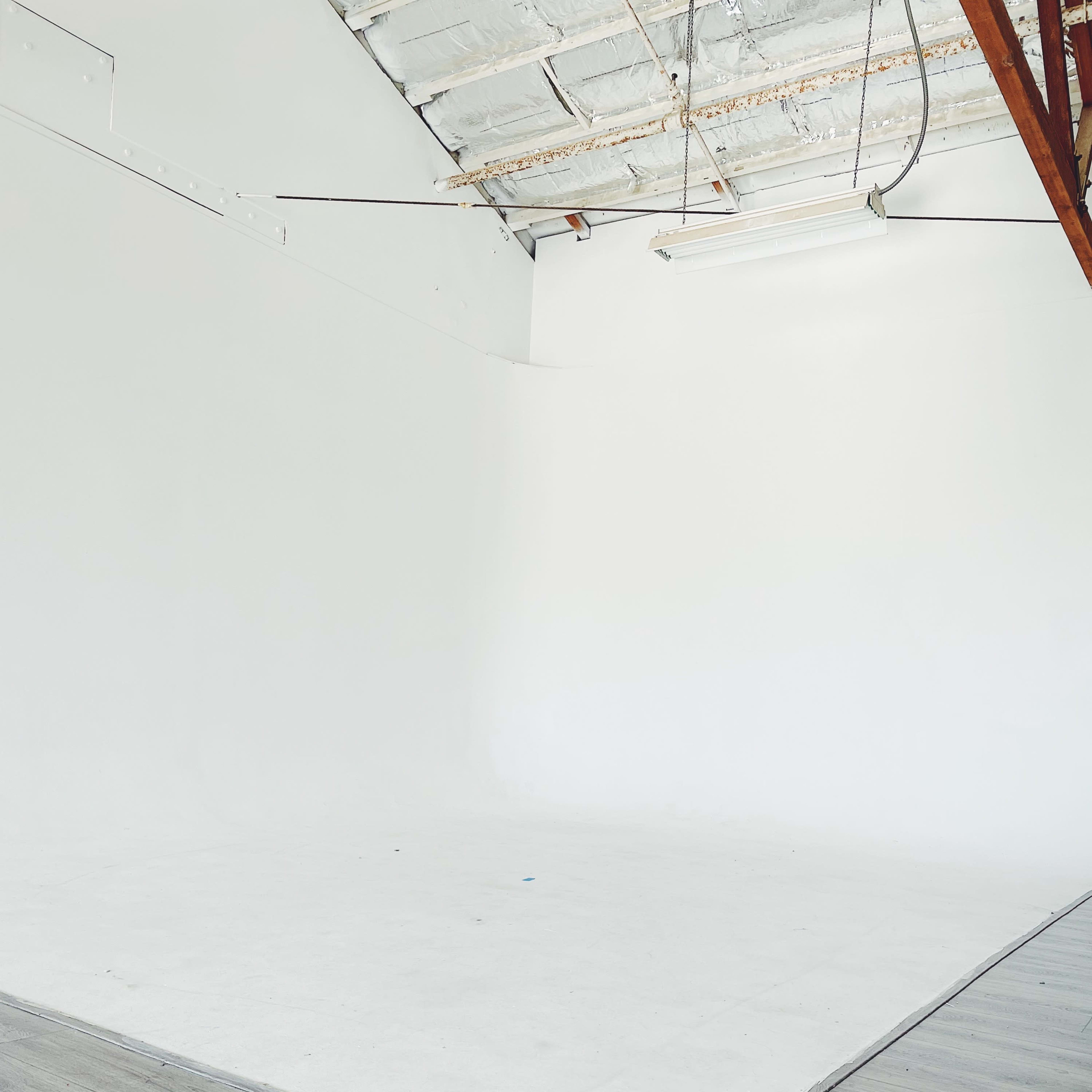 A spacious, empty studio with white walls and a light wood floor.