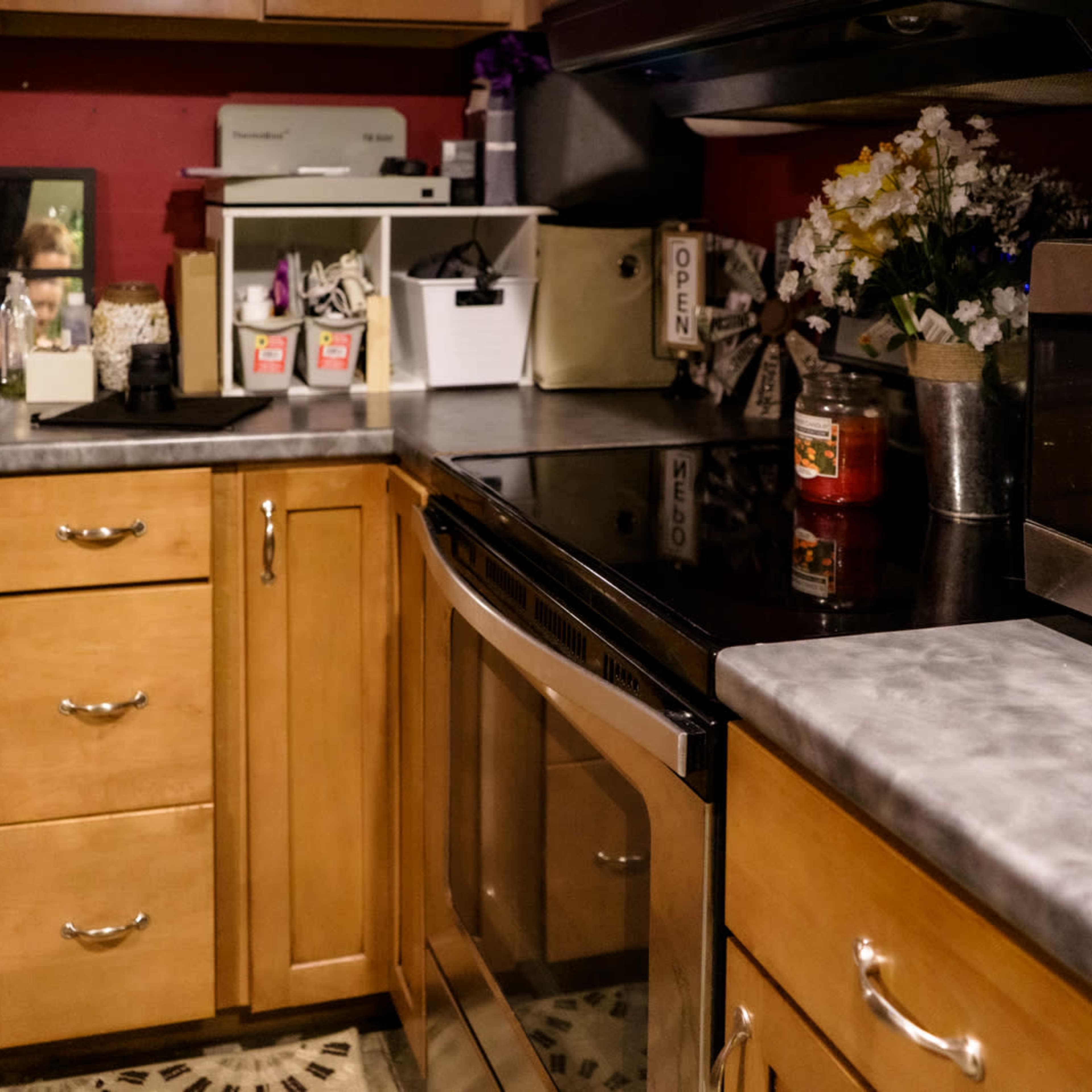 A kitchen with wooden cabinets, a black countertop, and a microwave next to a sink and a flower arrangement.