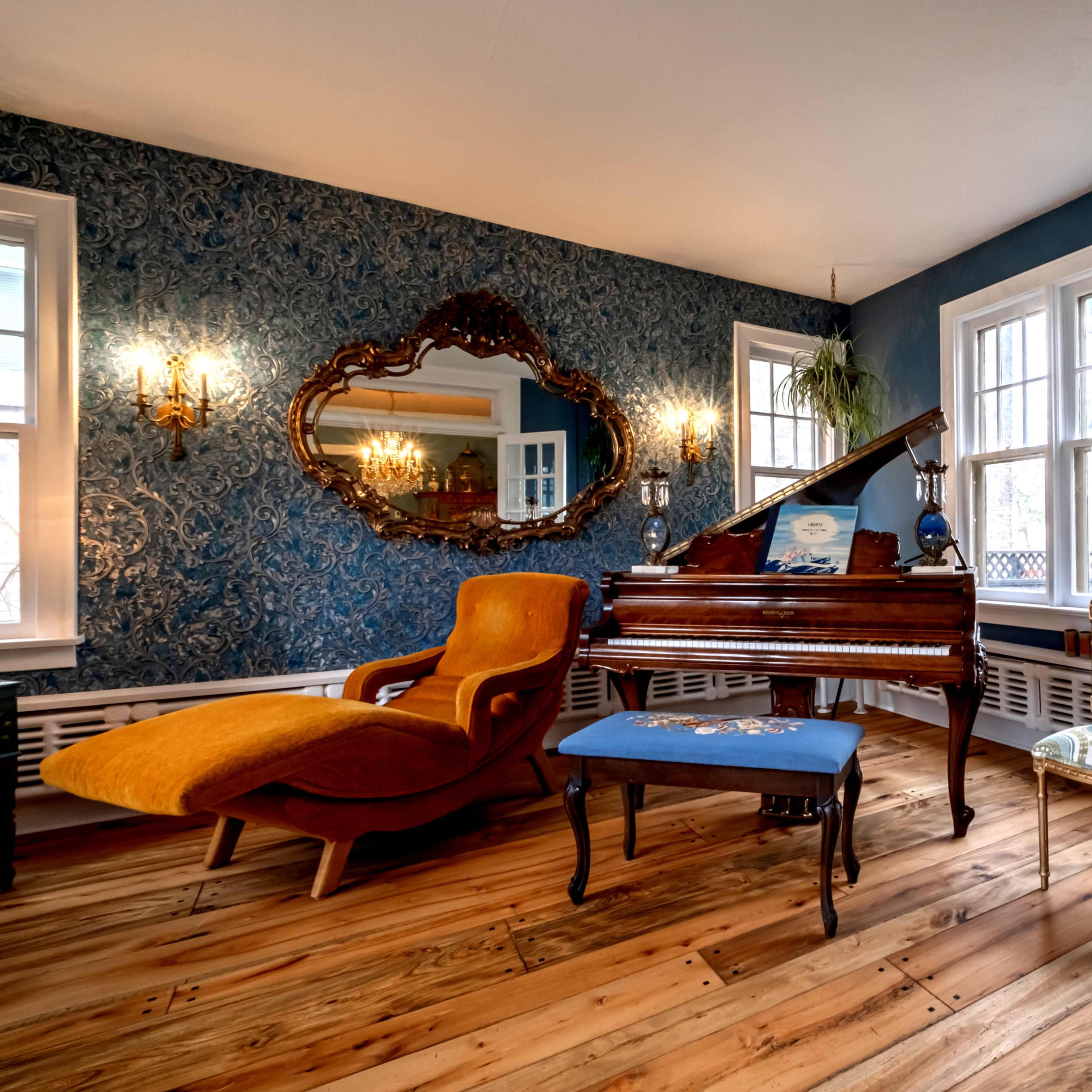 A cozy living room with a grand piano, a vintage lounge chair, and large windows allowing natural light to fill the space.