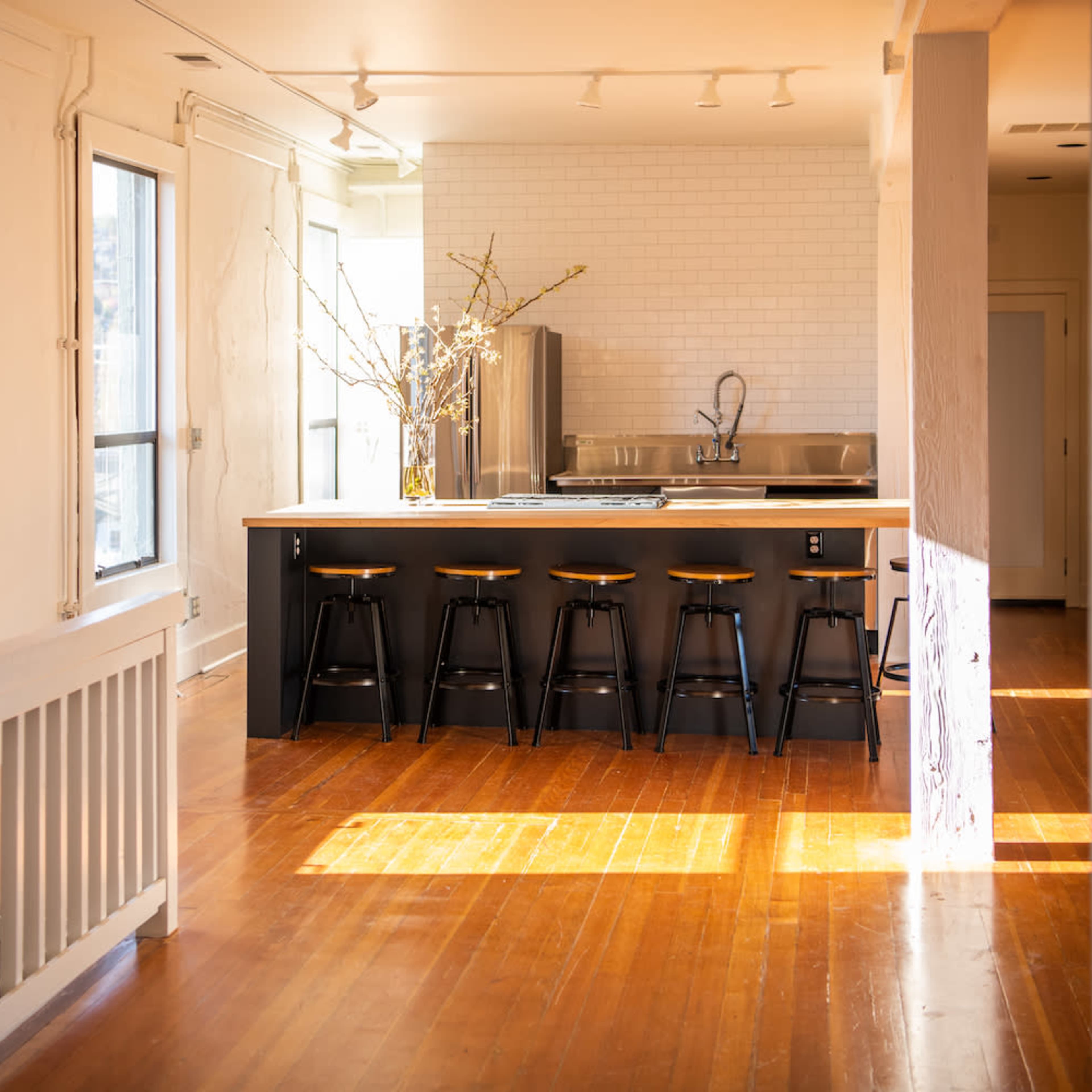 A spacious kitchen features a central island with seating and large windows allowing natural light to flood the room.