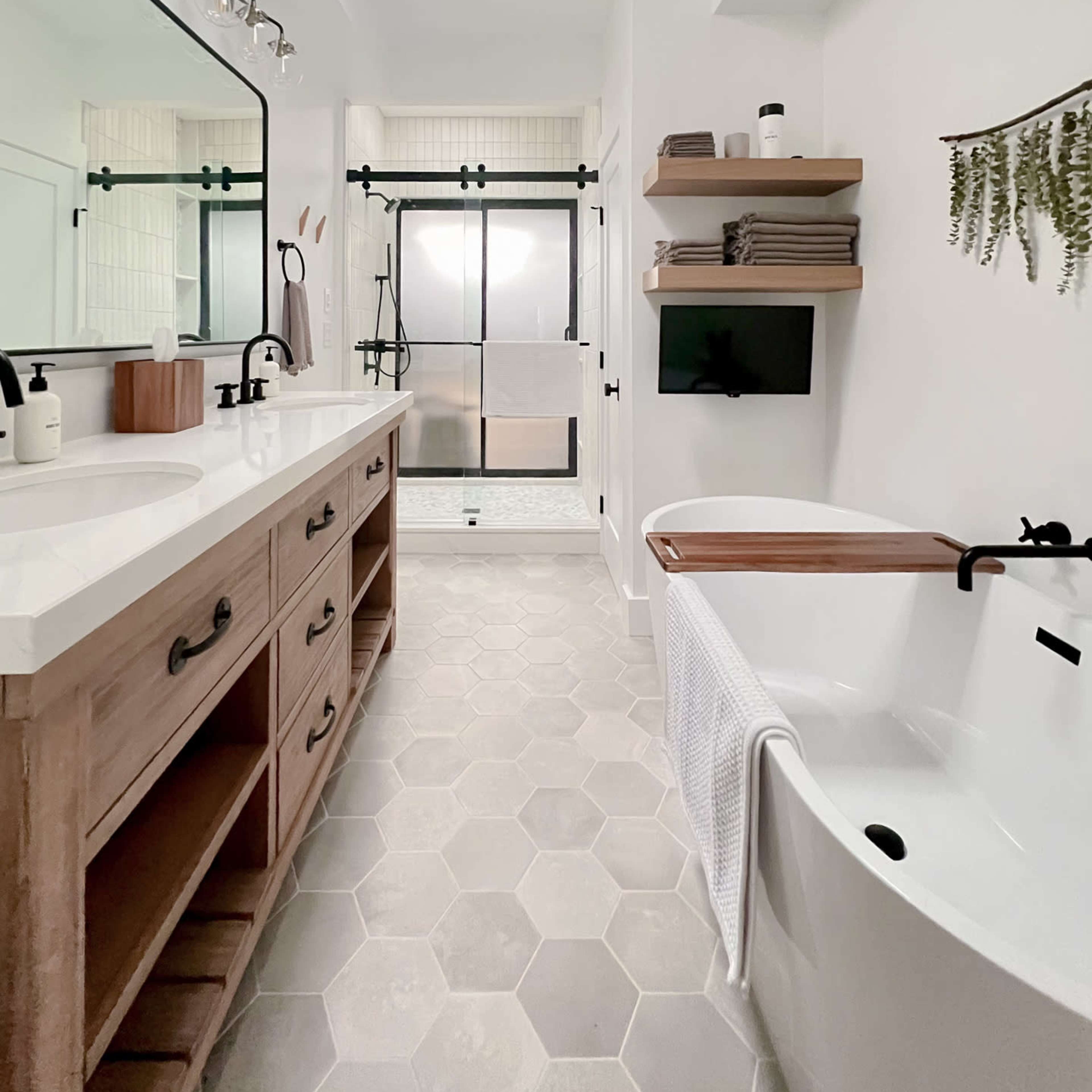 A spacious modern bathroom featuring a double sink vanity, a freestanding bathtub, and a walk-in shower with glass doors.