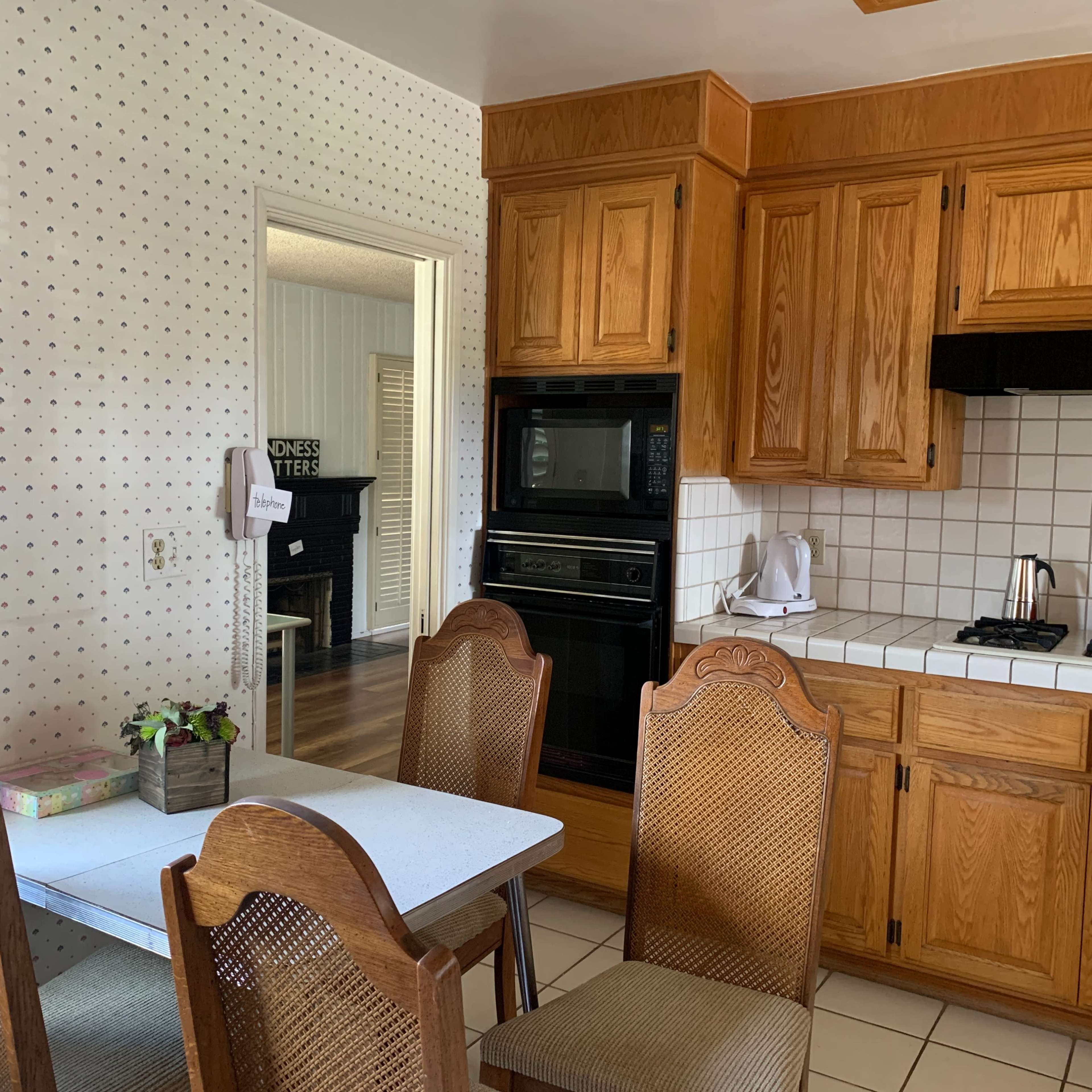 A kitchen featuring wooden cabinetry, a tiled floor, and a small dining table with four chairs.