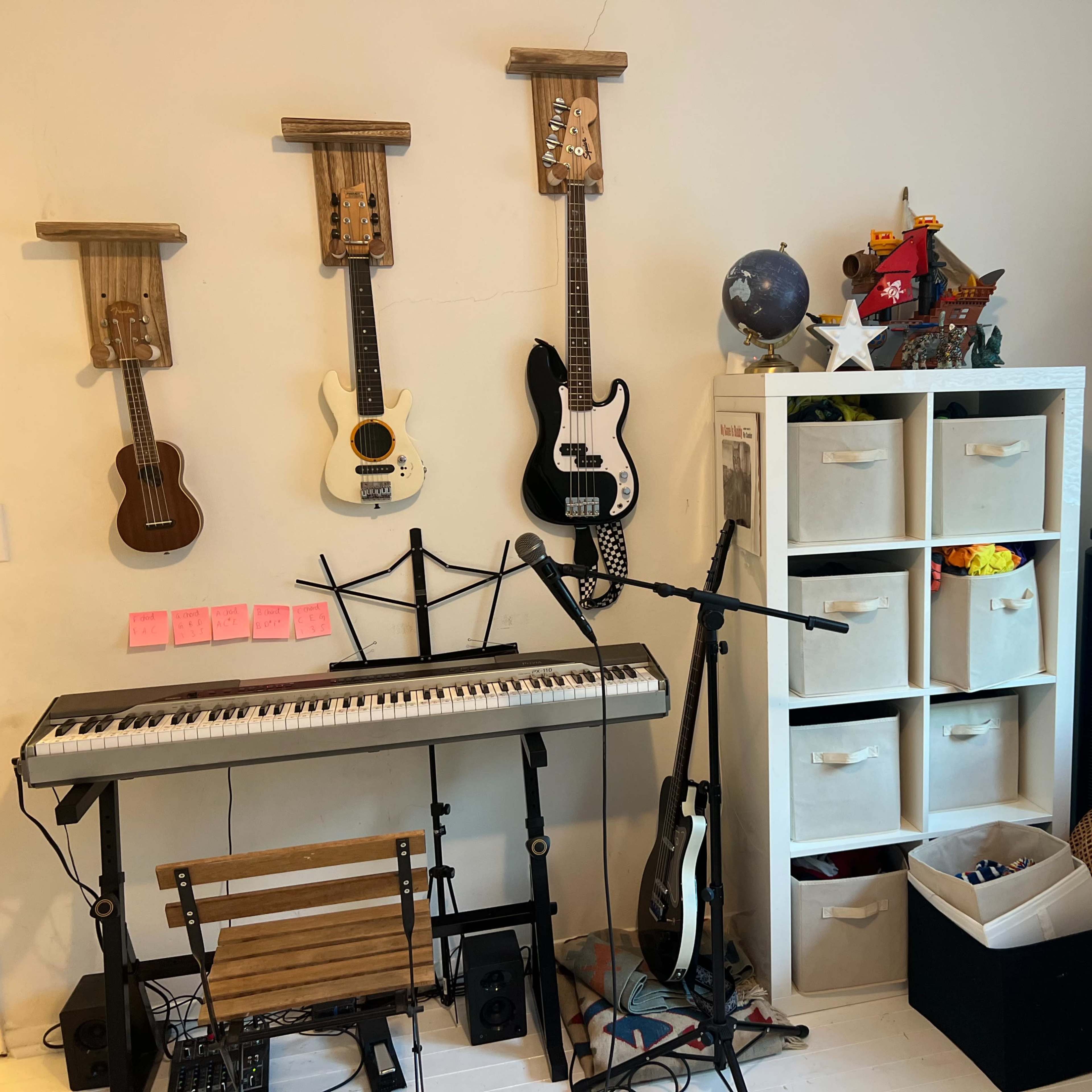 A music corner features a keyboard, guitars mounted on the wall, and storage bins filled with various items.