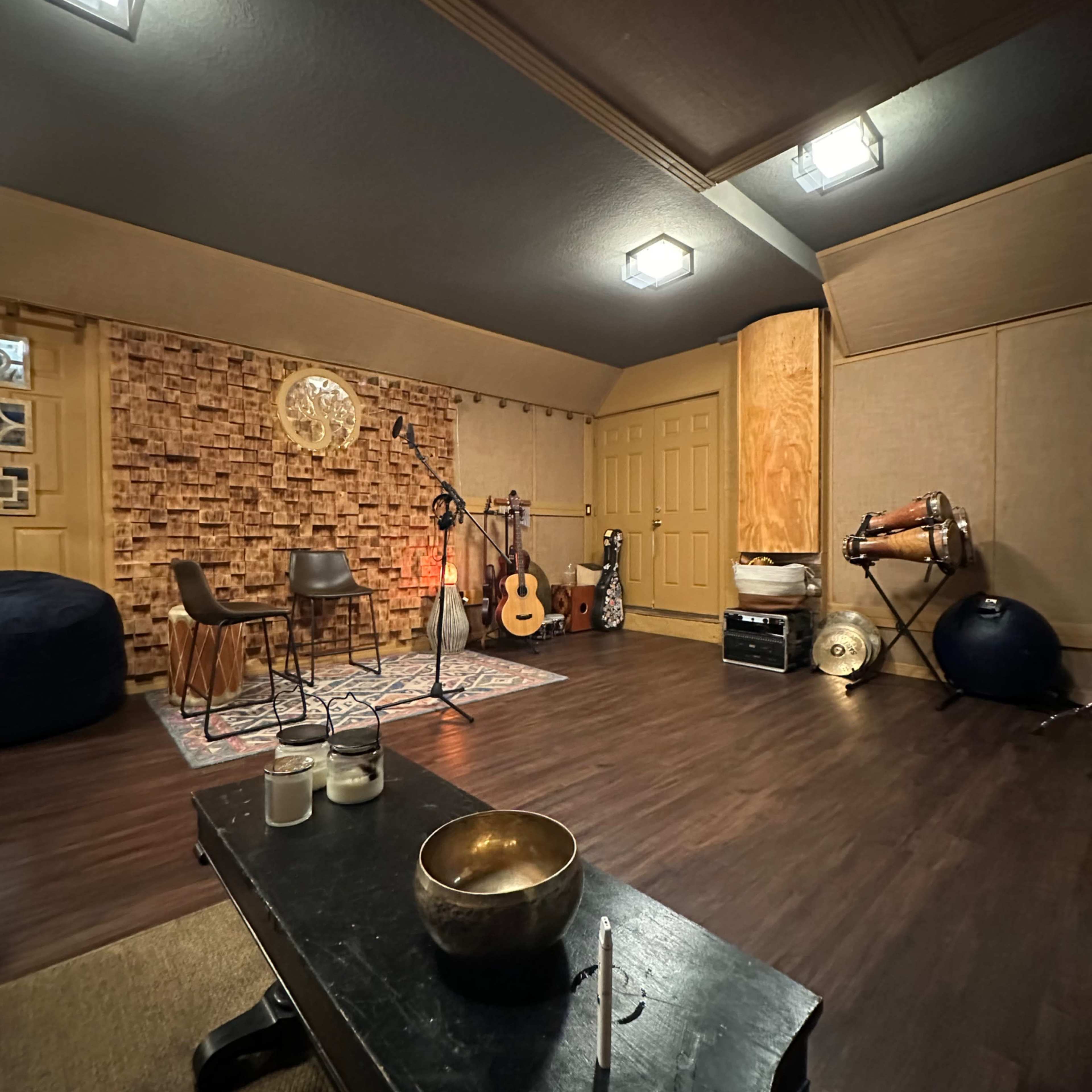 A music room with a wooden floor, soundproof walls, various instruments, and seating arranged for recording or practice.