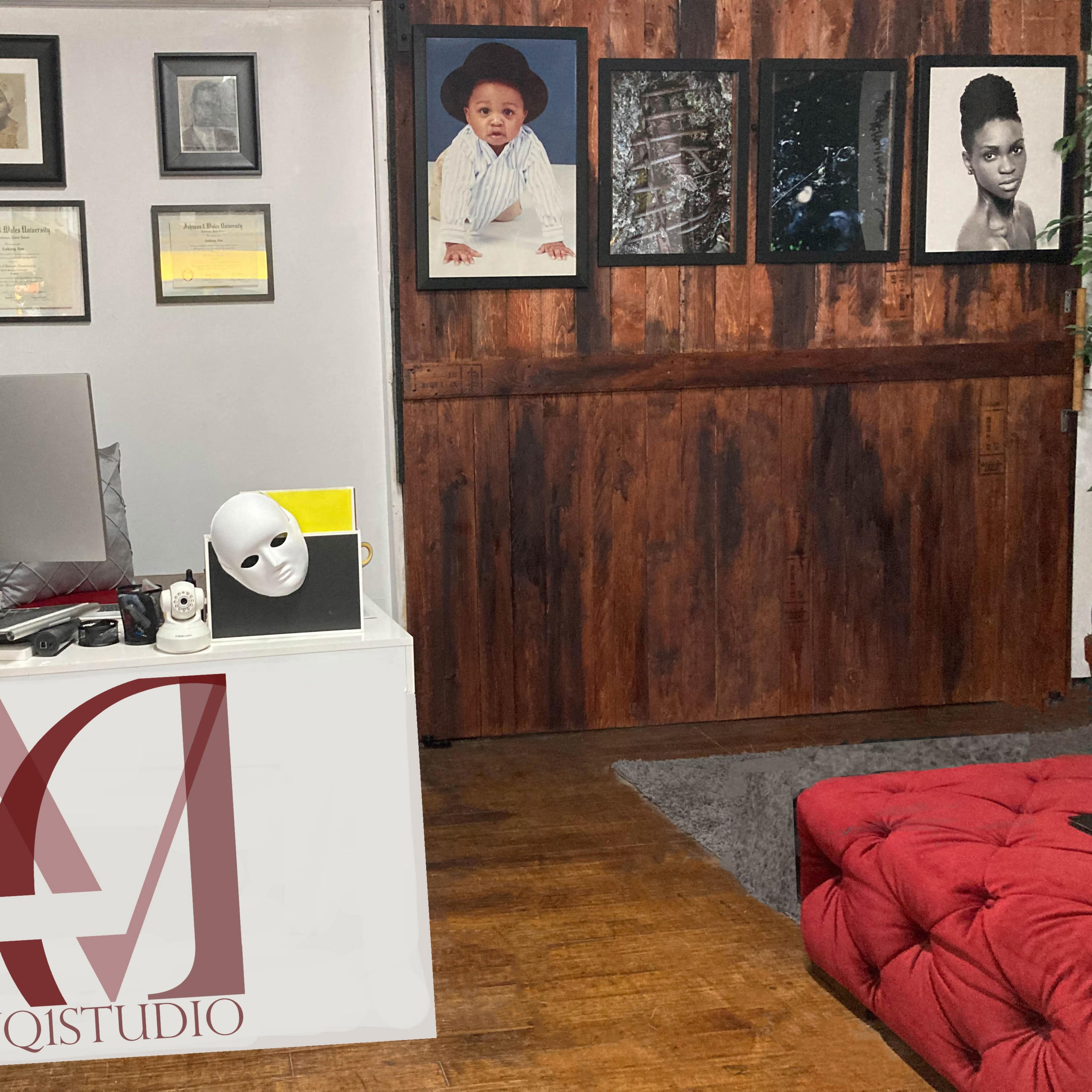 A modern studio space with a front desk displaying the logo "VQISTUDIO," a computer, and various framed certificates on the wall beside a wooden panel displaying black-and-white photographs.