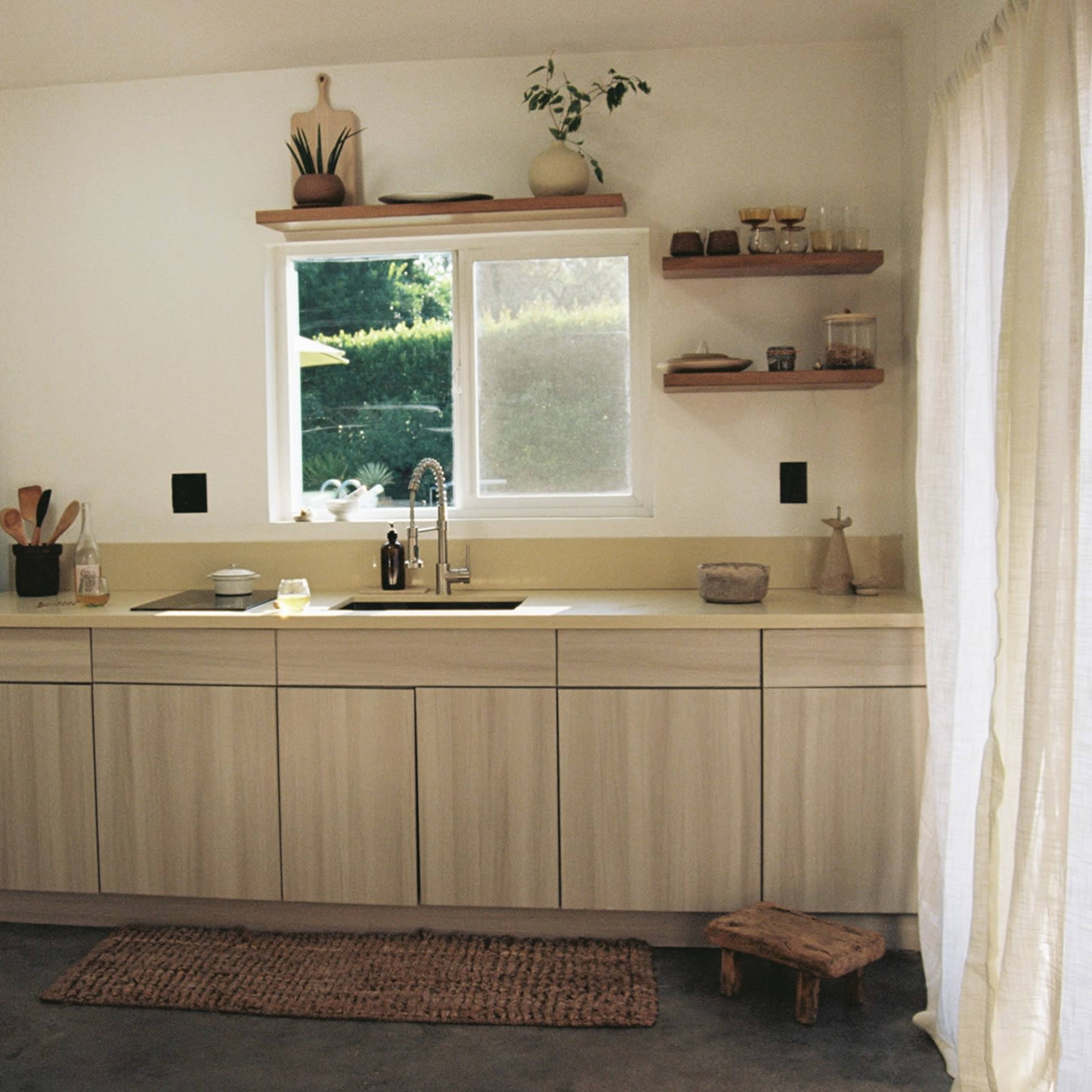 A kitchen with light wooden cabinetry, a window above the sink, and a vintage refrigerator.