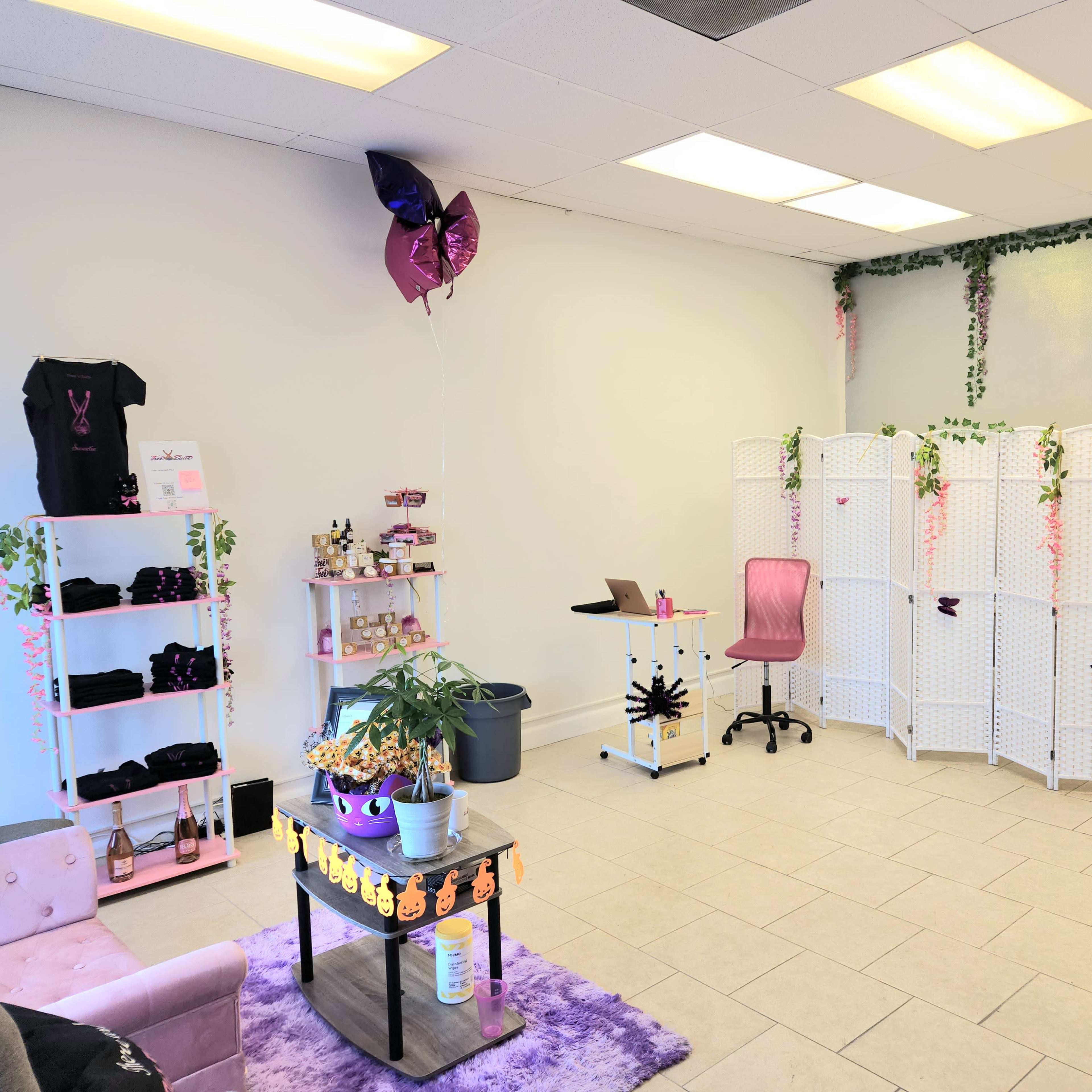 A bright, minimalist boutique or salon space with a mix of seating, decorative partitions, and plants.