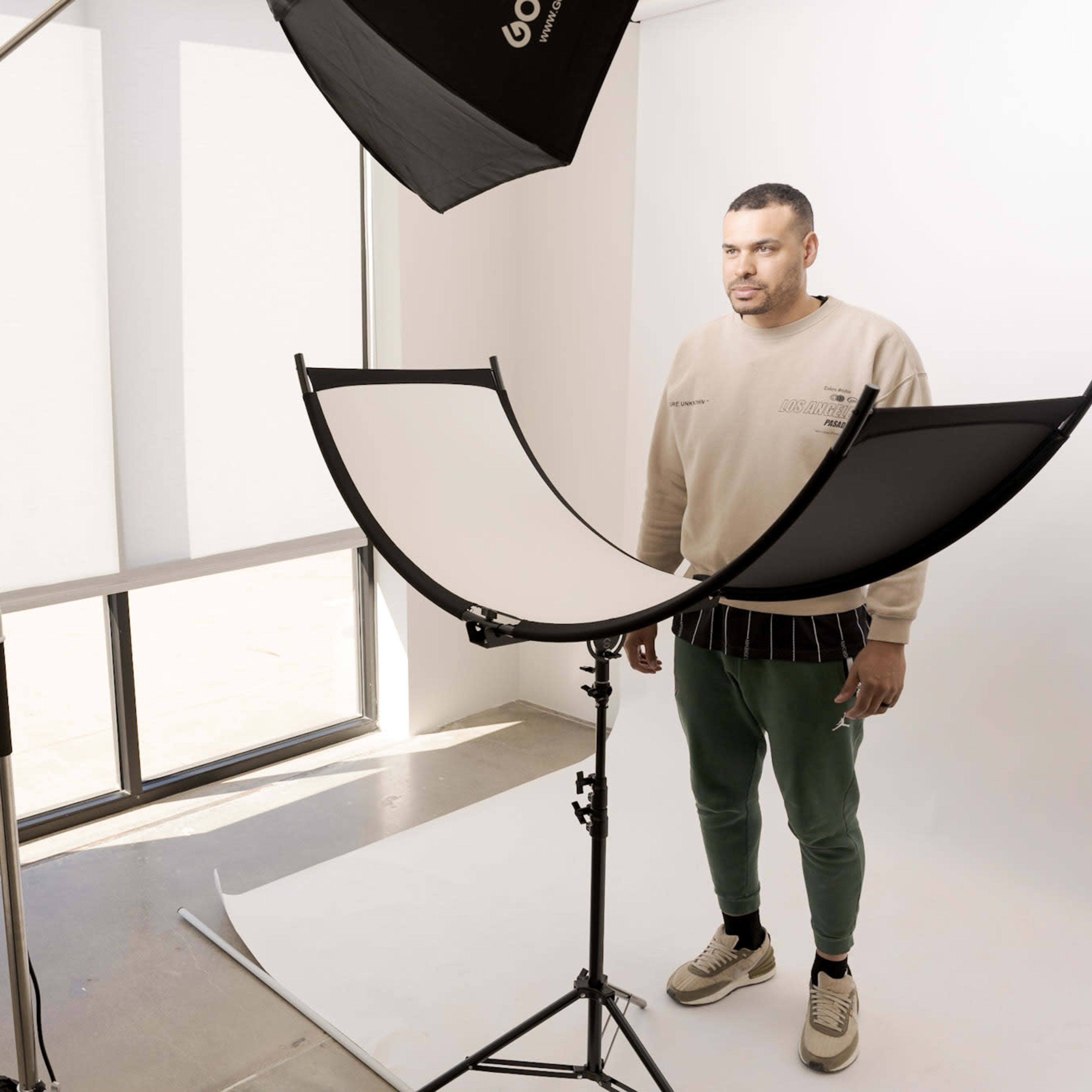A photographer captures a model in a studio with a softbox and reflector setup.