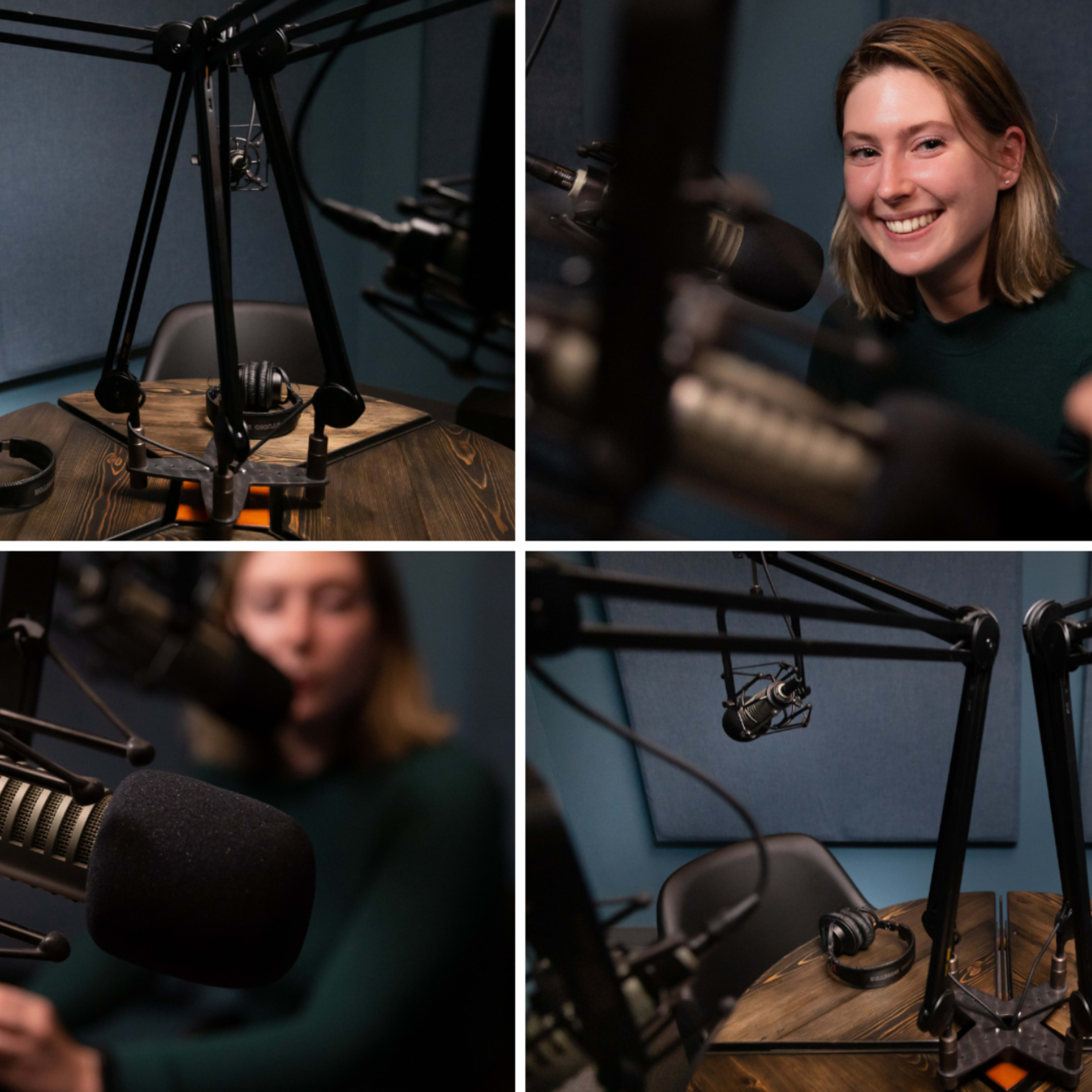 A podcast recording studio with microphones and headphones set up on a wooden table, featuring a smiling individual in a green sweater.