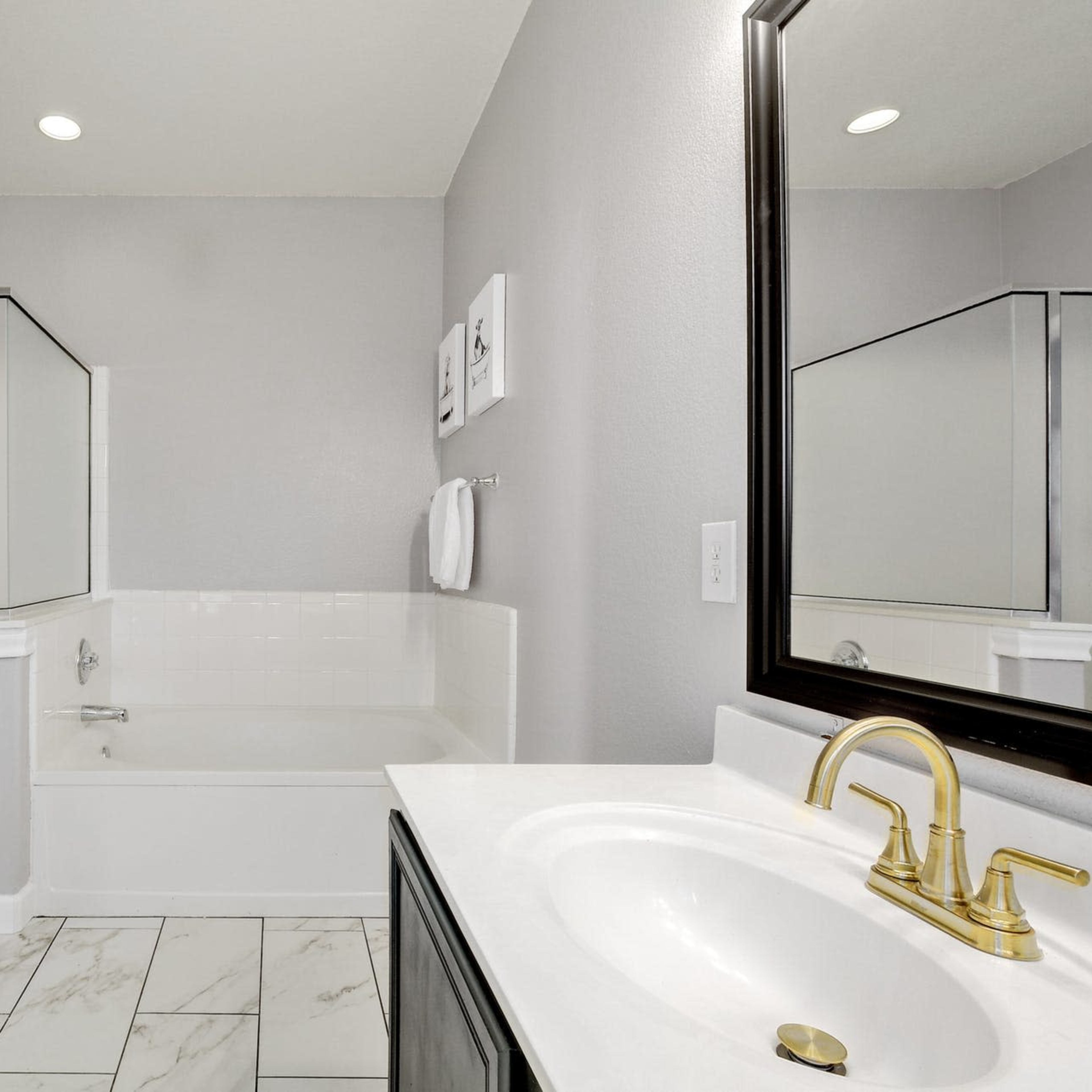 A modern bathroom featuring a glass-enclosed shower, a bathtub, and a vanity with a sink and mirror.