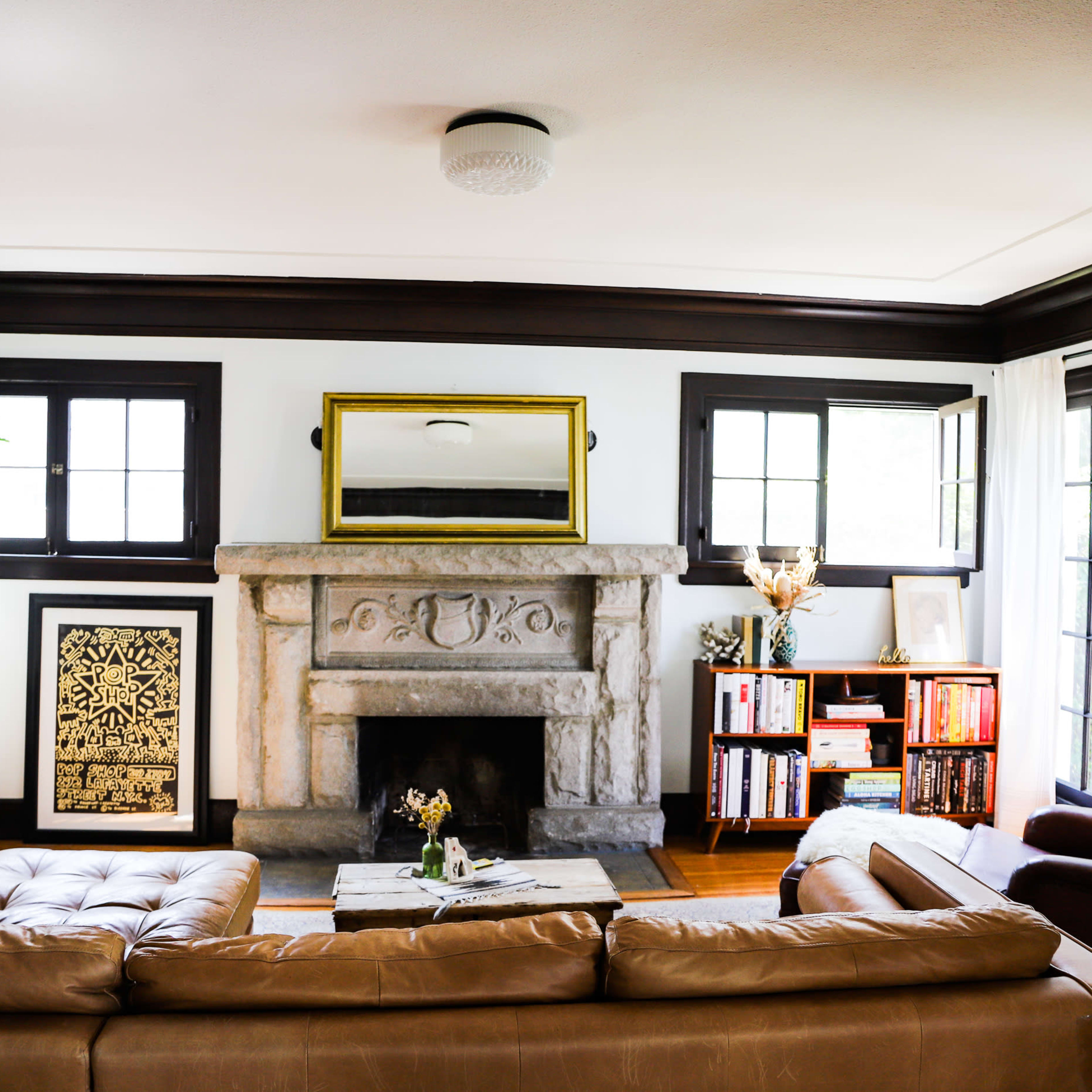 A cozy living room with a stone fireplace as a focal point, flanked by bookshelves and windows.